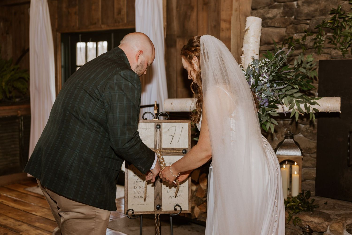Rustic barn wedding ceremony with white fabric draping and wooden beams creating a romantic ambiance.