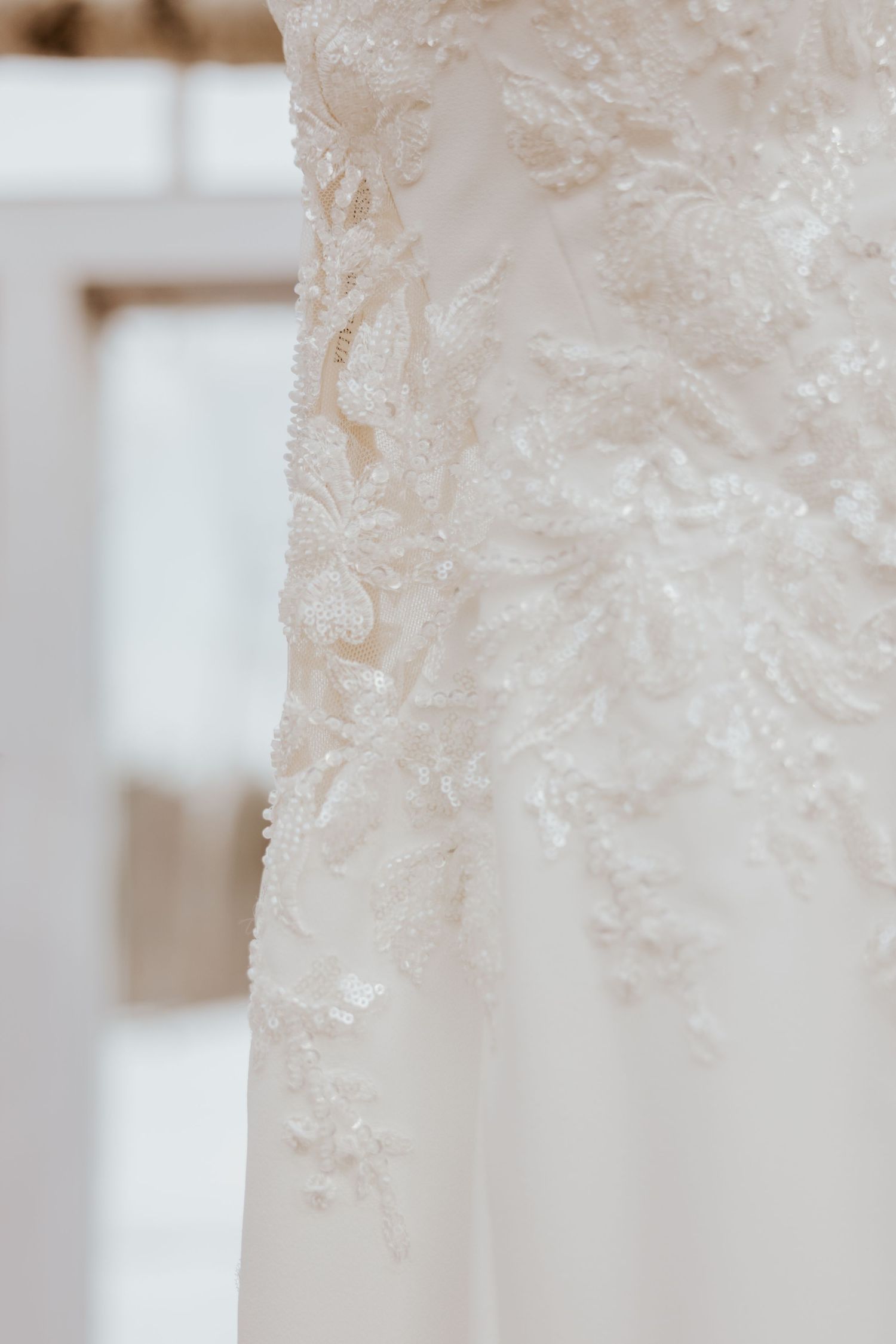 Close-up detail of intricate beaded lace embroidery on a elegant white wedding gown bodice.