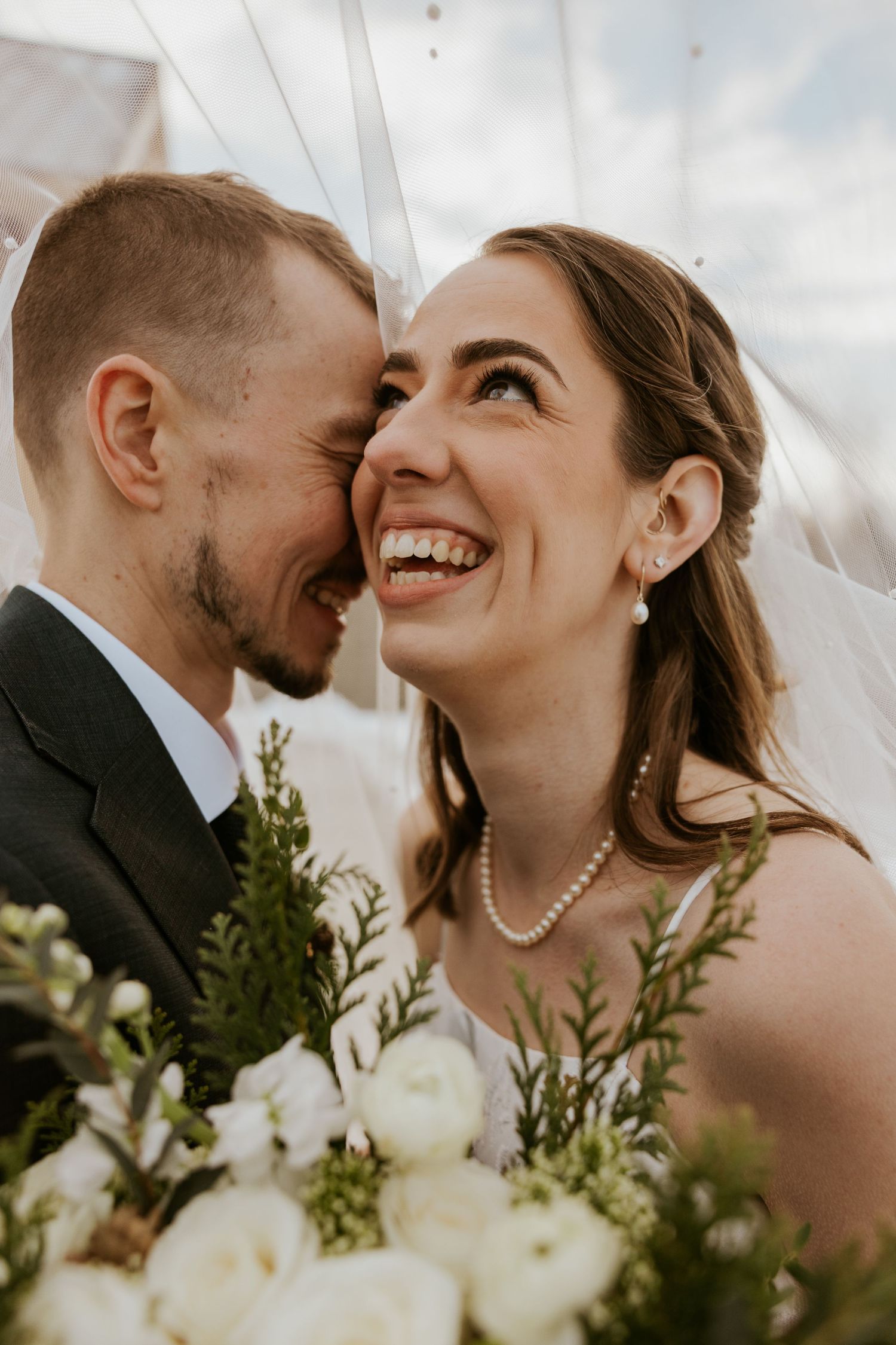 A romantic wedding couple shares intimate moments among white floral arrangements and greenery in a series of close-up shots.