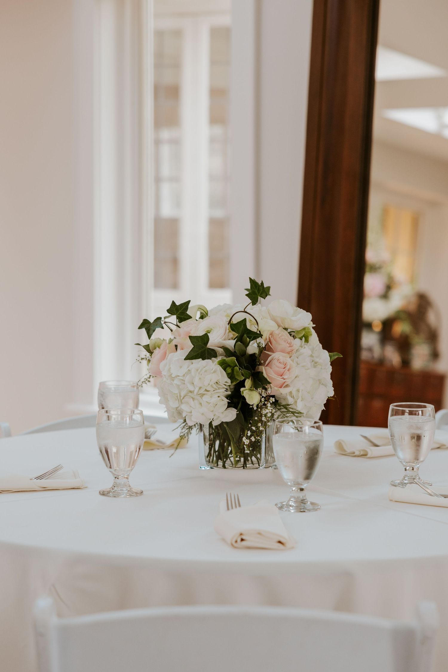 Elegant wedding reception table settings with white floral centerpieces and crystal glassware on crisp linens.