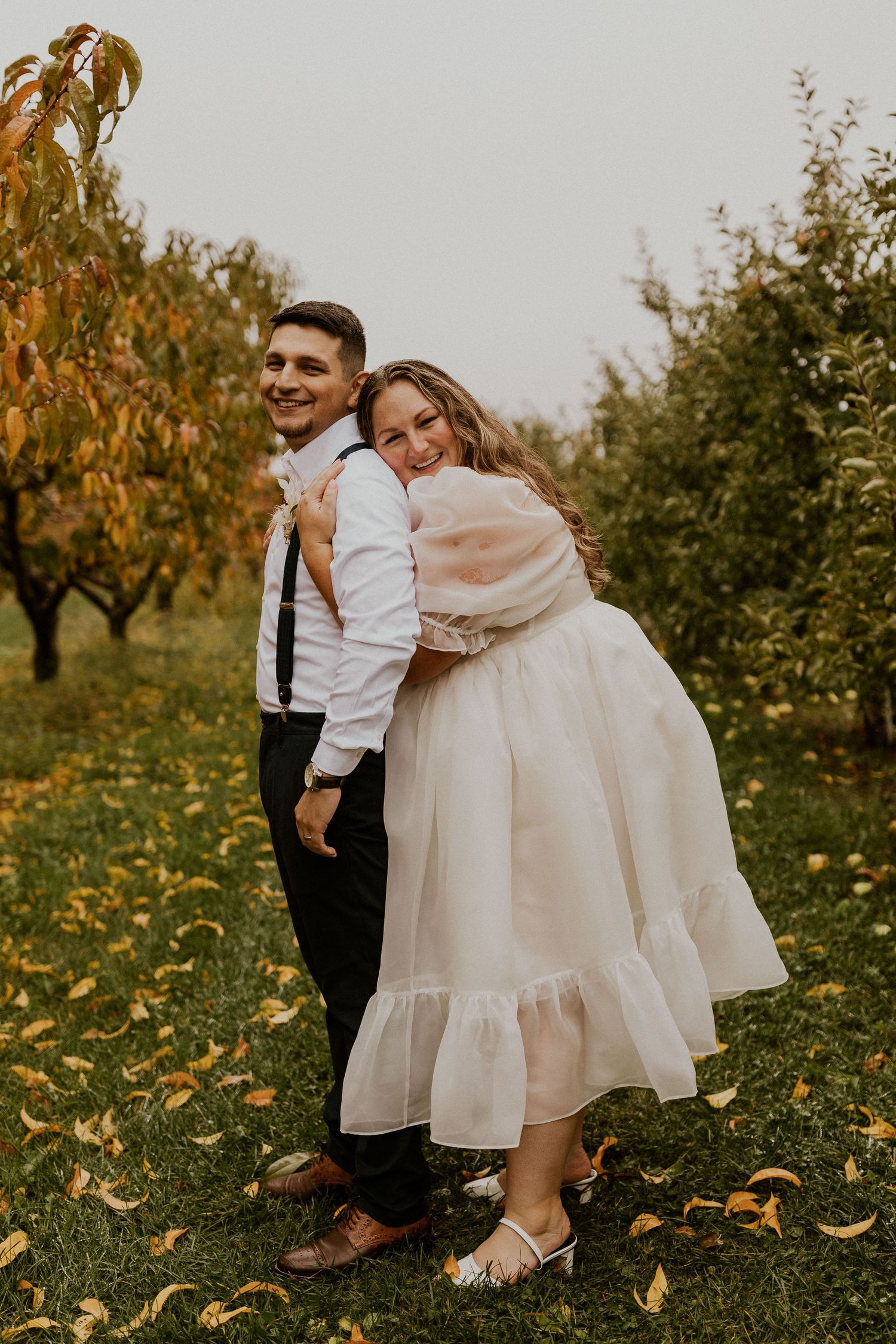 Terise and Jose kissing in between the rows of apple trees at Carter Hill Orchard in Concord New Hampshire]