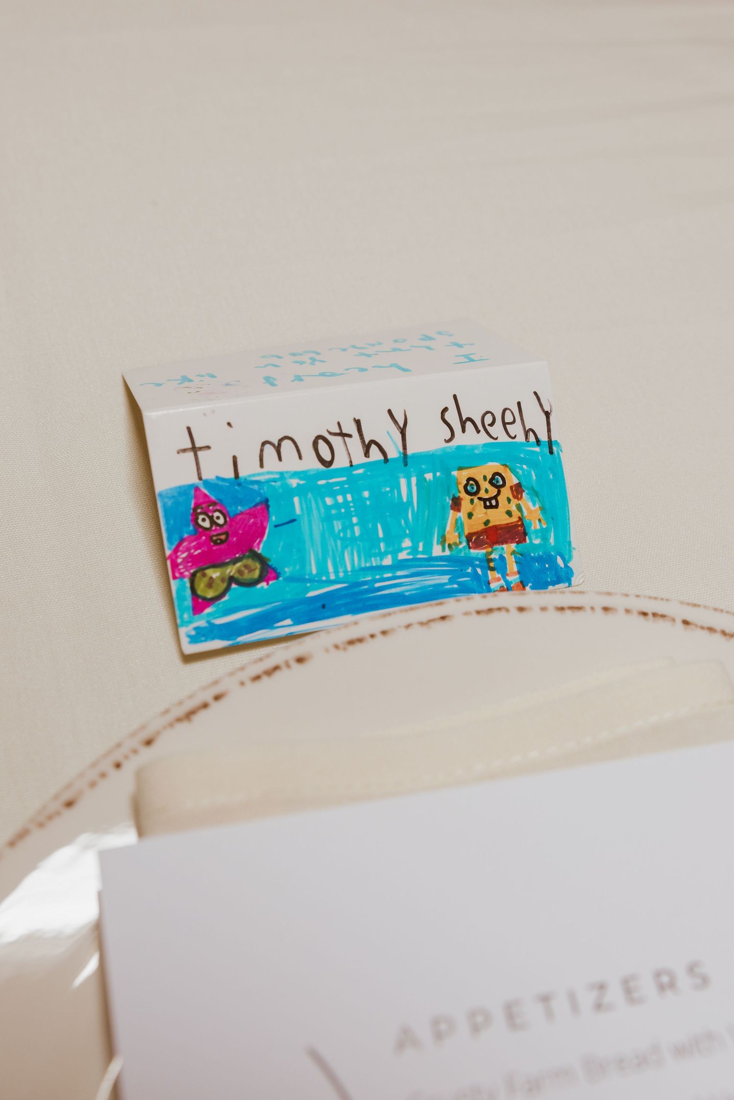 Handmade kids place card reading Timothy Sheehy with colorful owl drawings at a wedding reception dinner.