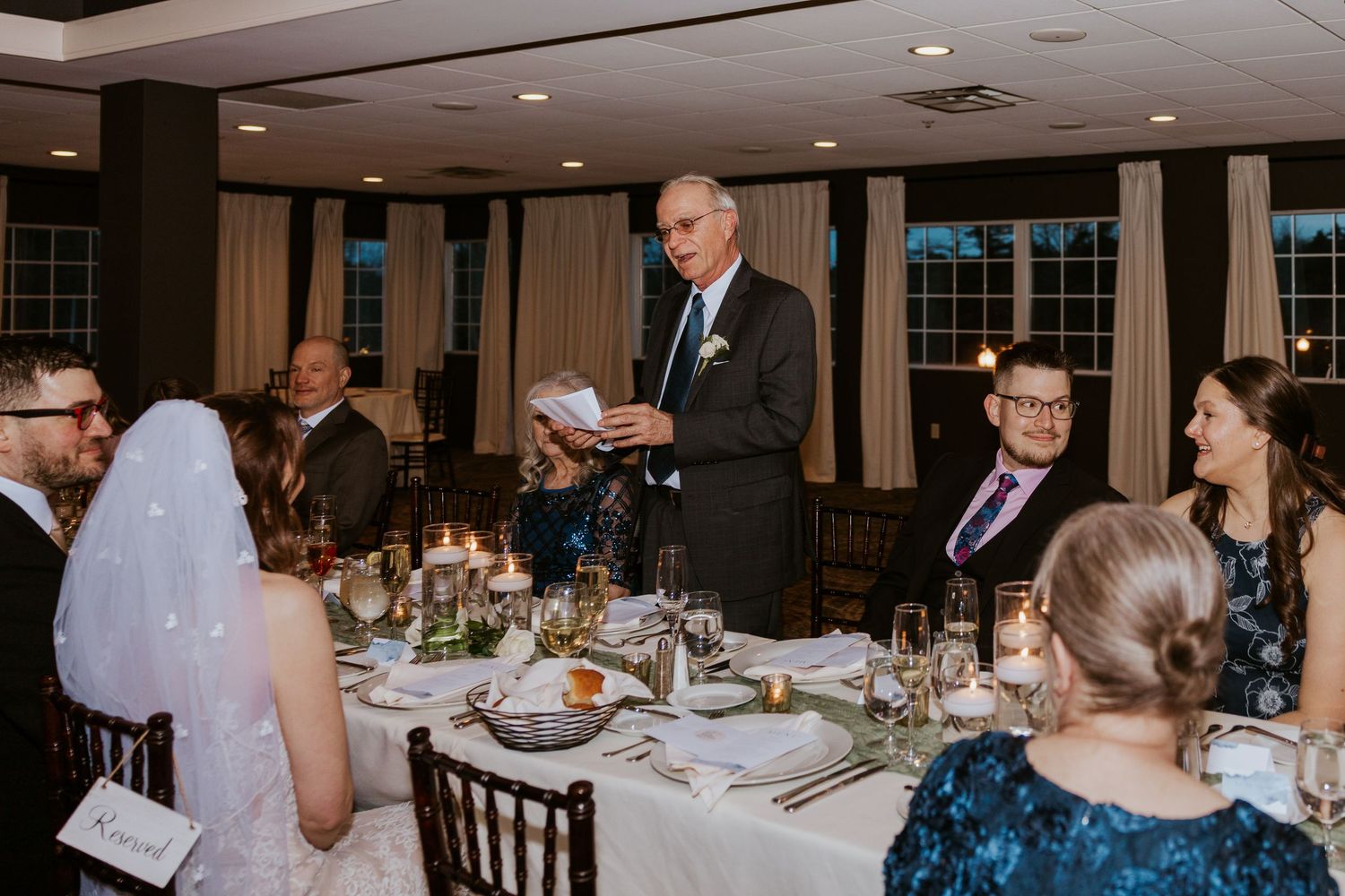 Wedding reception dining room with elegant table settings and warm lighting.