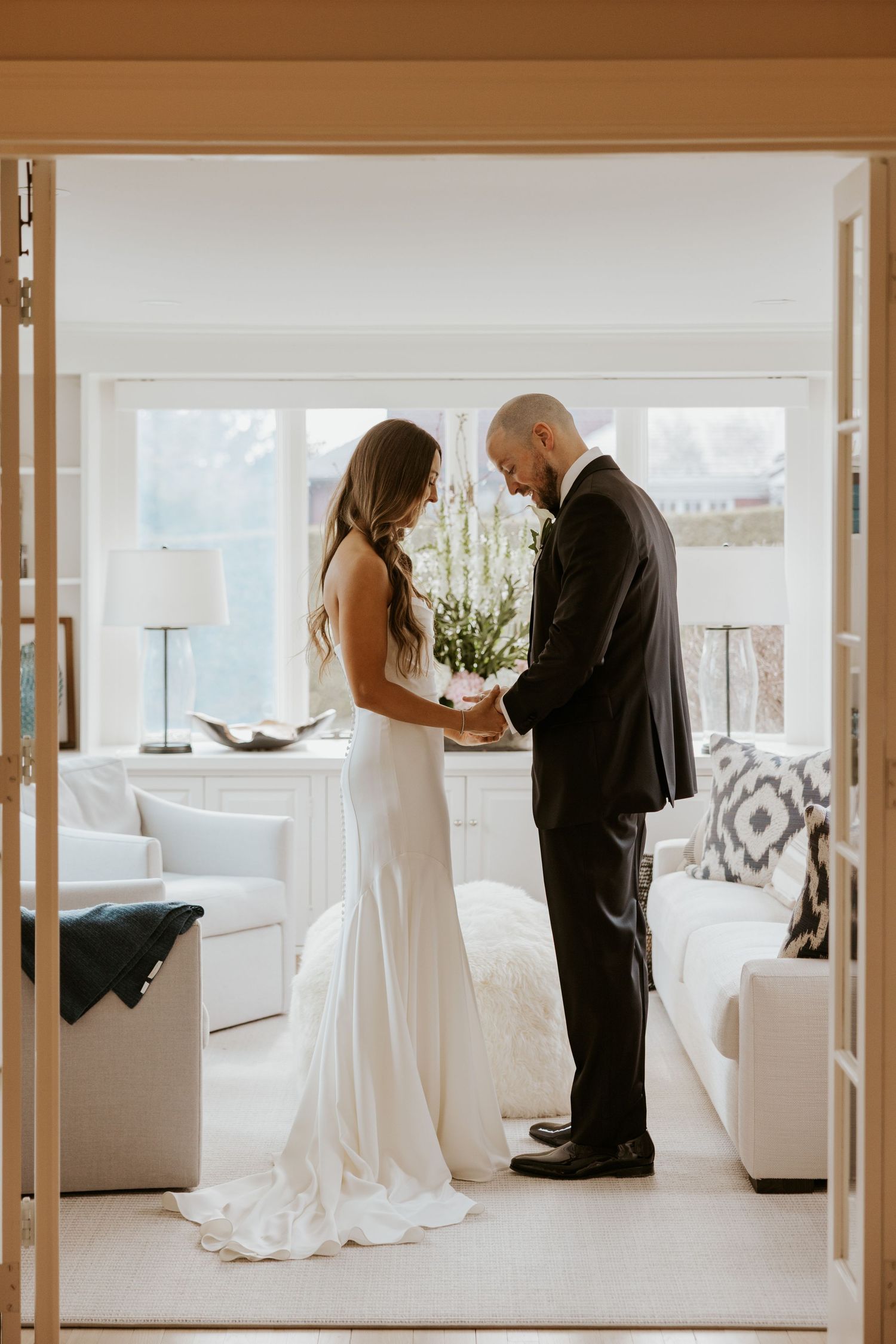 An intimate wedding first look captured in a bright modern living room with white decor.