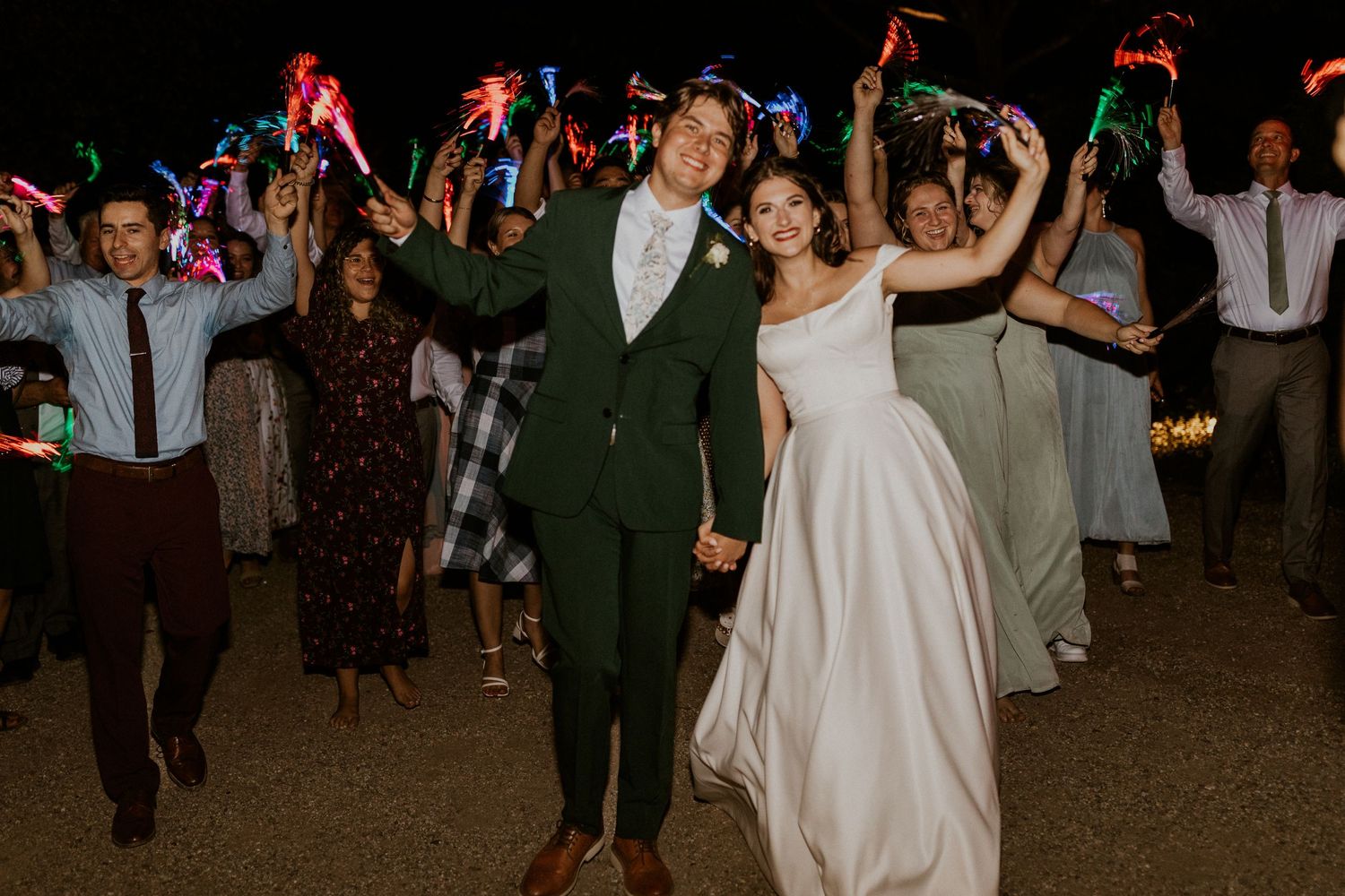 Wedding celebration with guests waving colorful glow sticks on the dance floor.