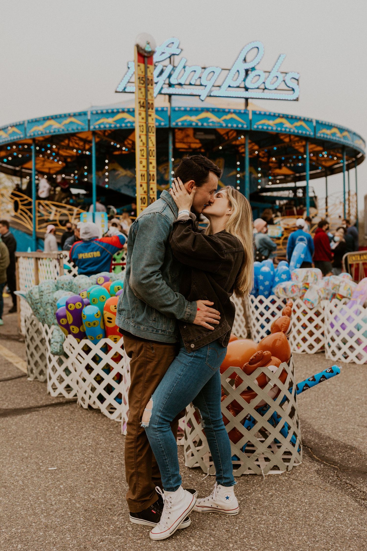 Couple dancing playfully in front of a vintage carnival ride.