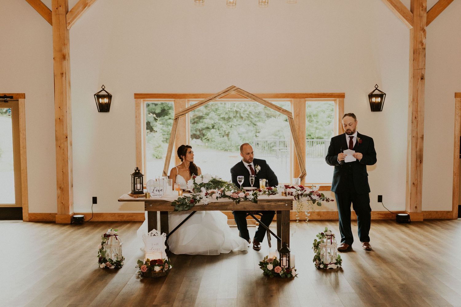 Wedding venue interior featuring rustic wooden posts and elegant table settings.