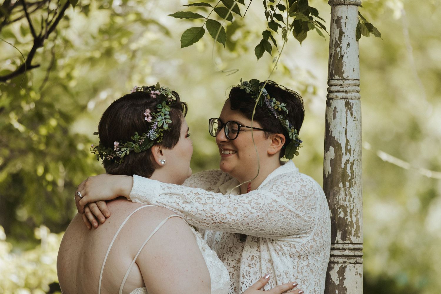 A romantic outdoor wedding moment captured between two people in white lace attire.