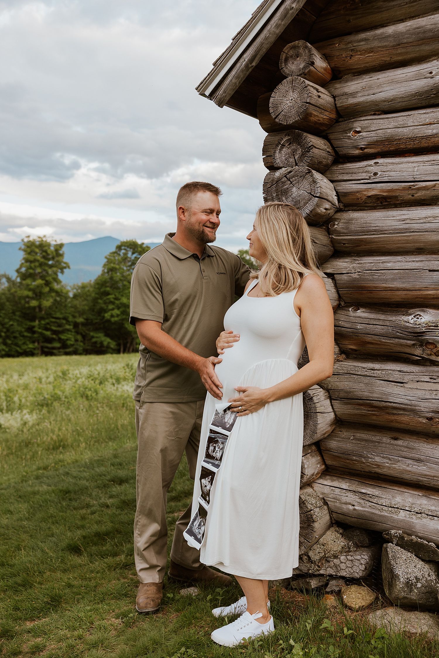 NH couple taking materntiy pictures in the White Mountains, posing with their ultrasound pictures
