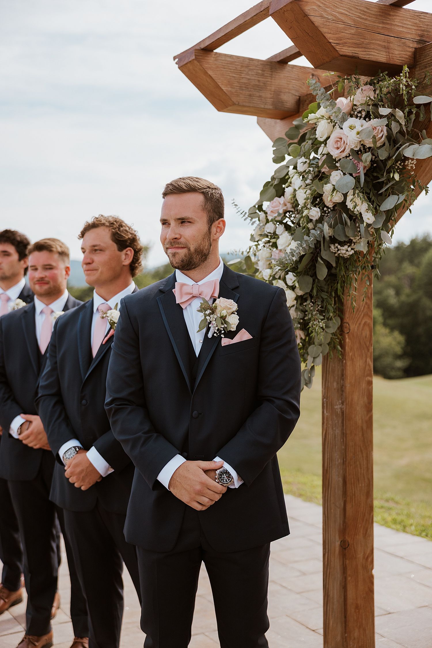 Groom in a navy suit waiting at the altar at his New Hampshire wedding ceremony at Owl's Nest