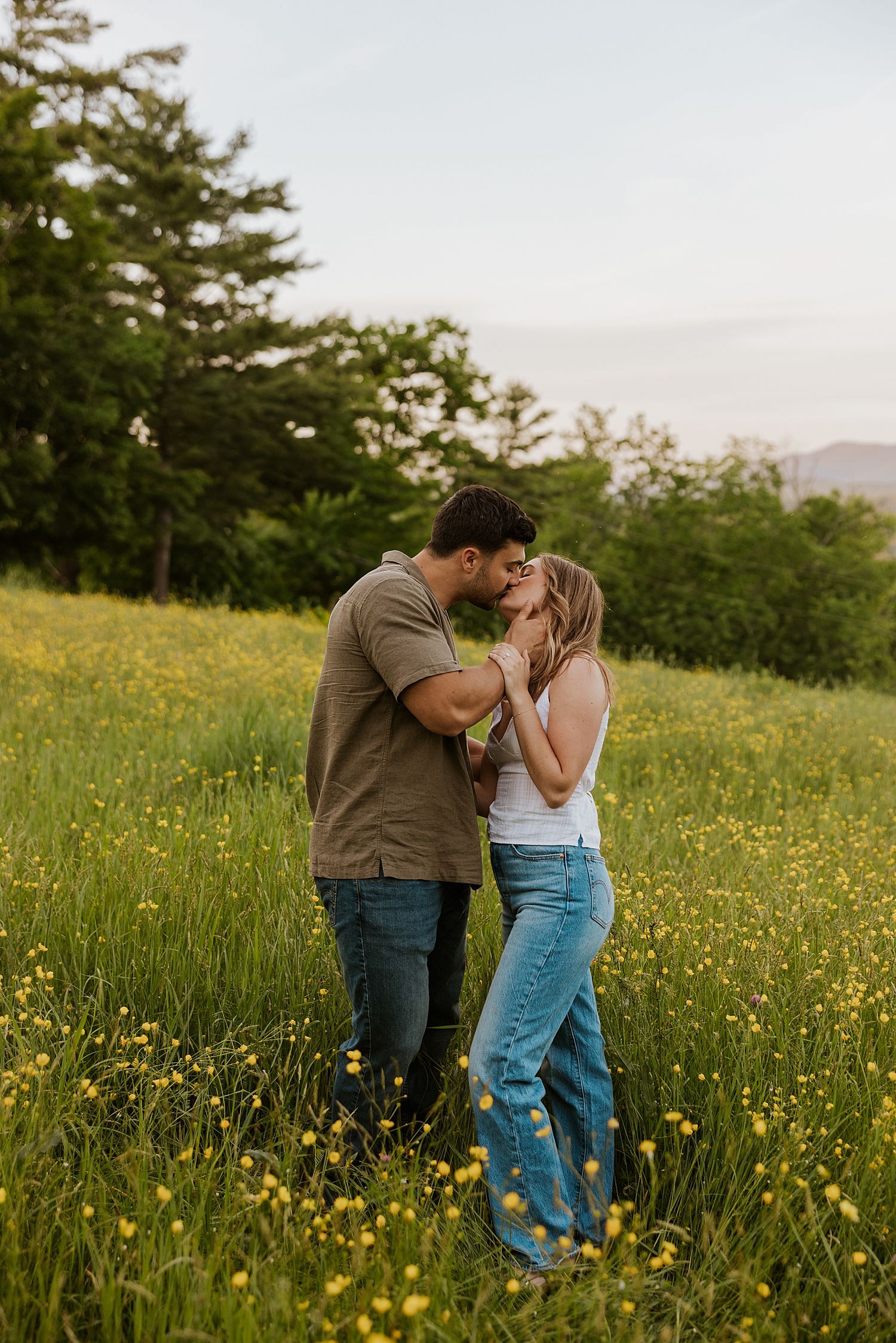 NH couple taking golden hour engagement photos in a wildflower field