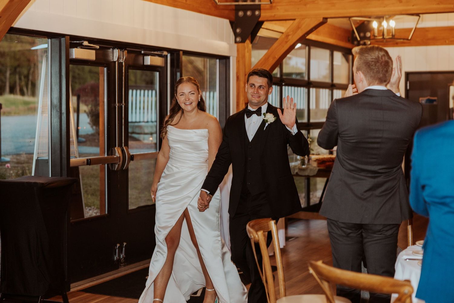 Bride and groom make grand entrance into elegant wedding reception venue holding hands.