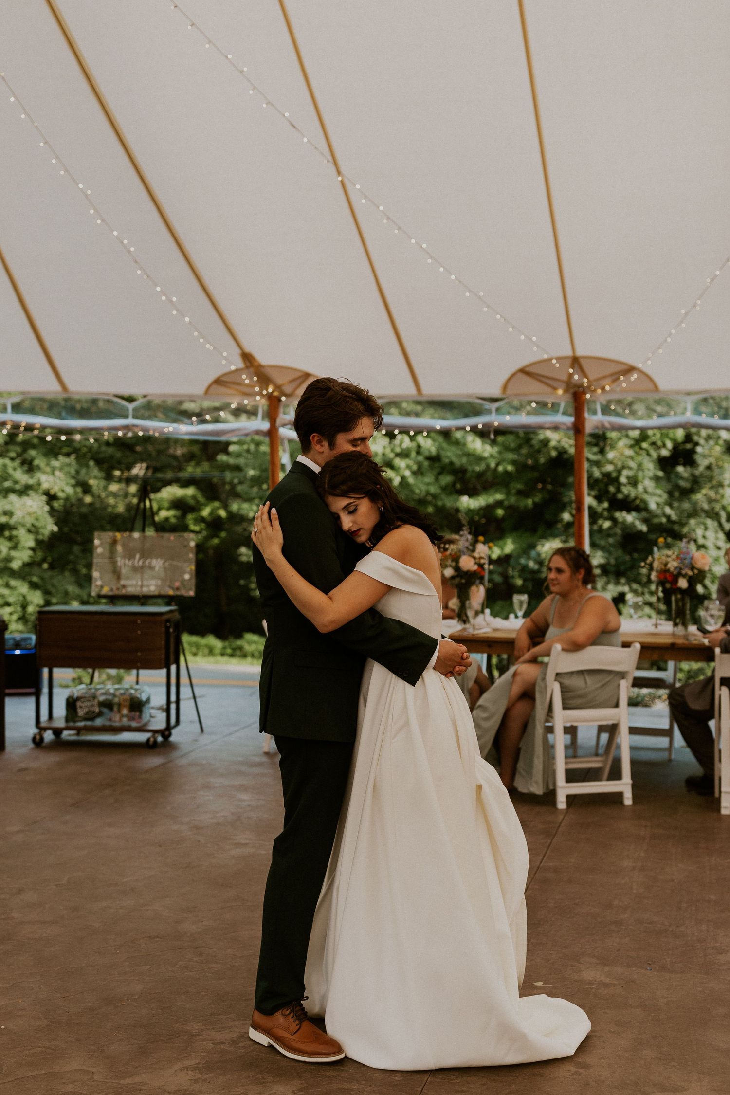 Couples dancing together under a white tent at an outdoor wedding reception.