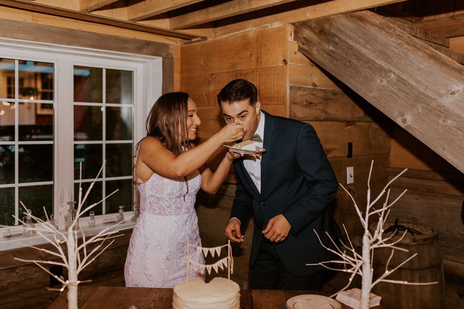 Couple dancing together in an elegantly lit rustic barn setting with white decor elements.