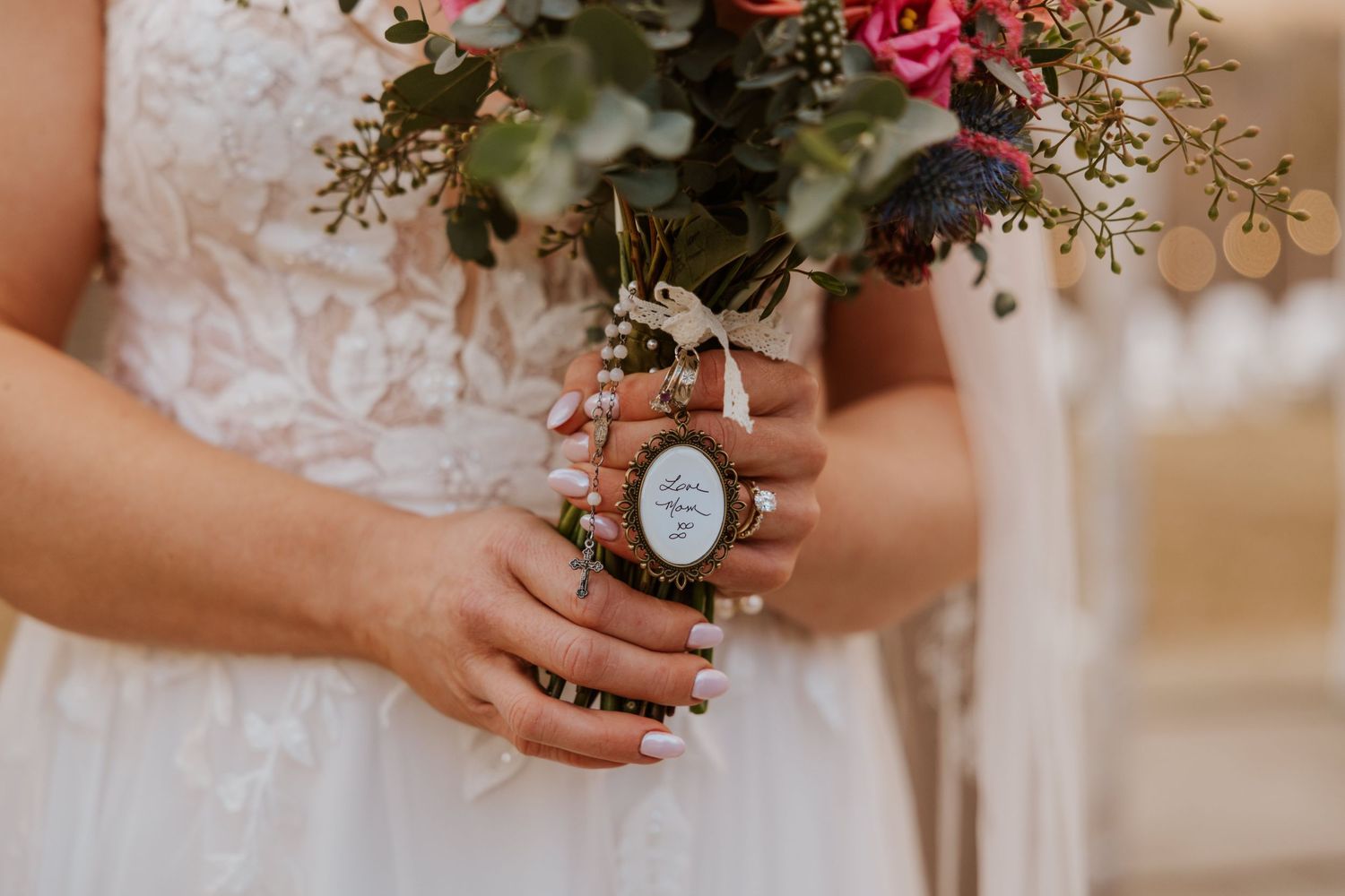 Close-up of wedding bouquet with pink and red flowers and natural greenery.