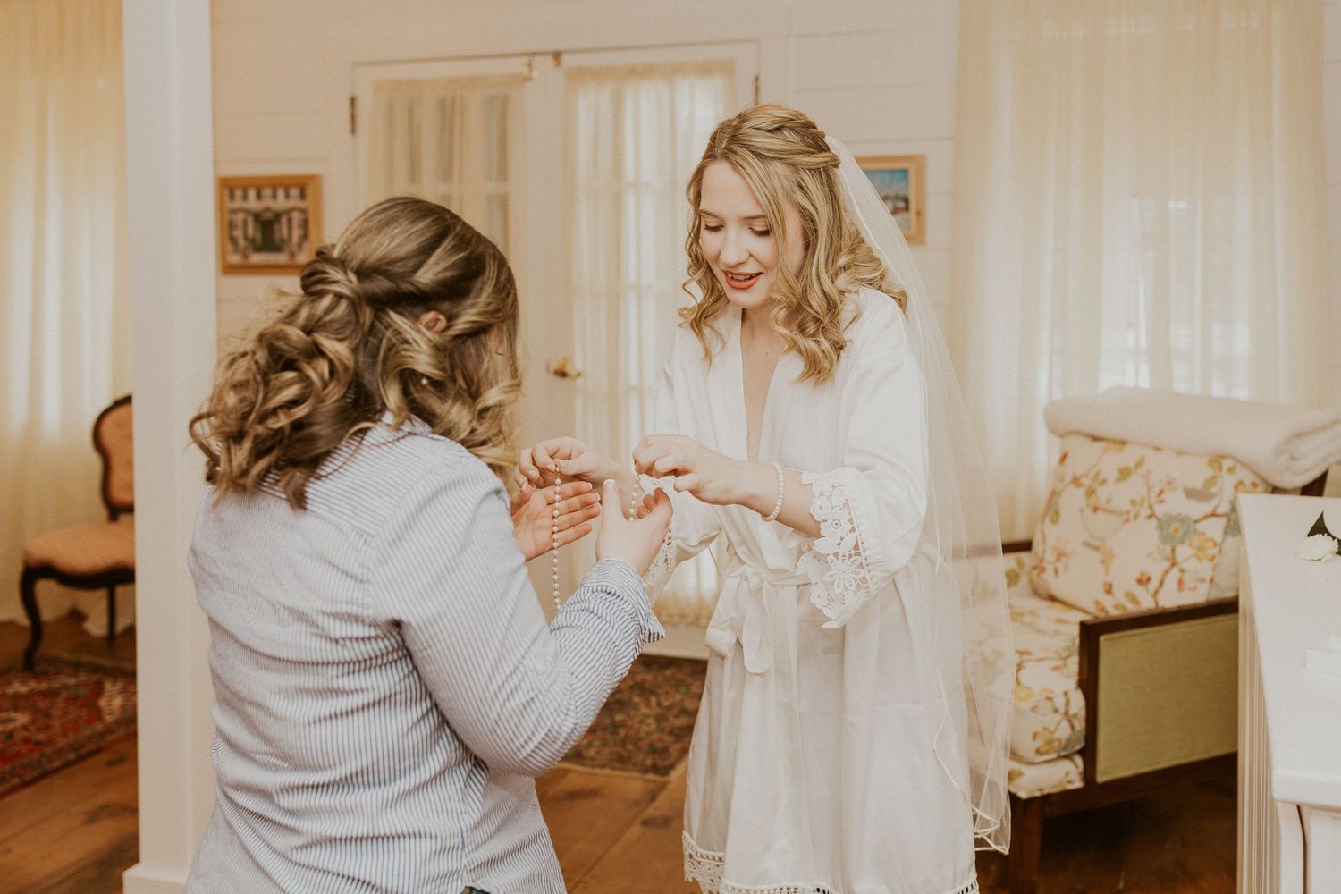 Deirdre is applying her jewelry with the help of her bridesmaids.