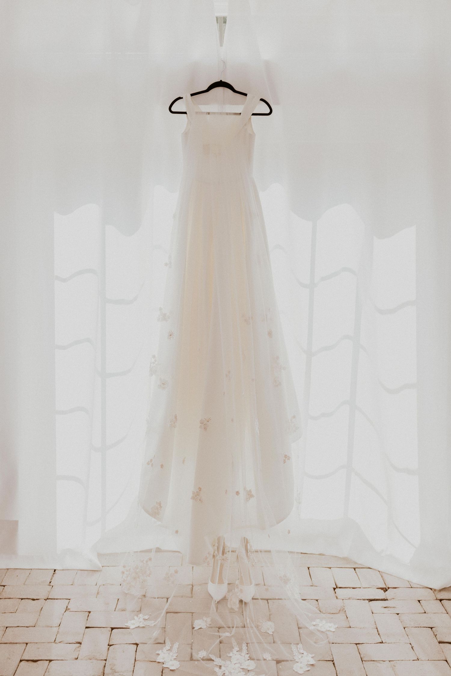 White wedding dress hanging elegantly against a light backdrop.