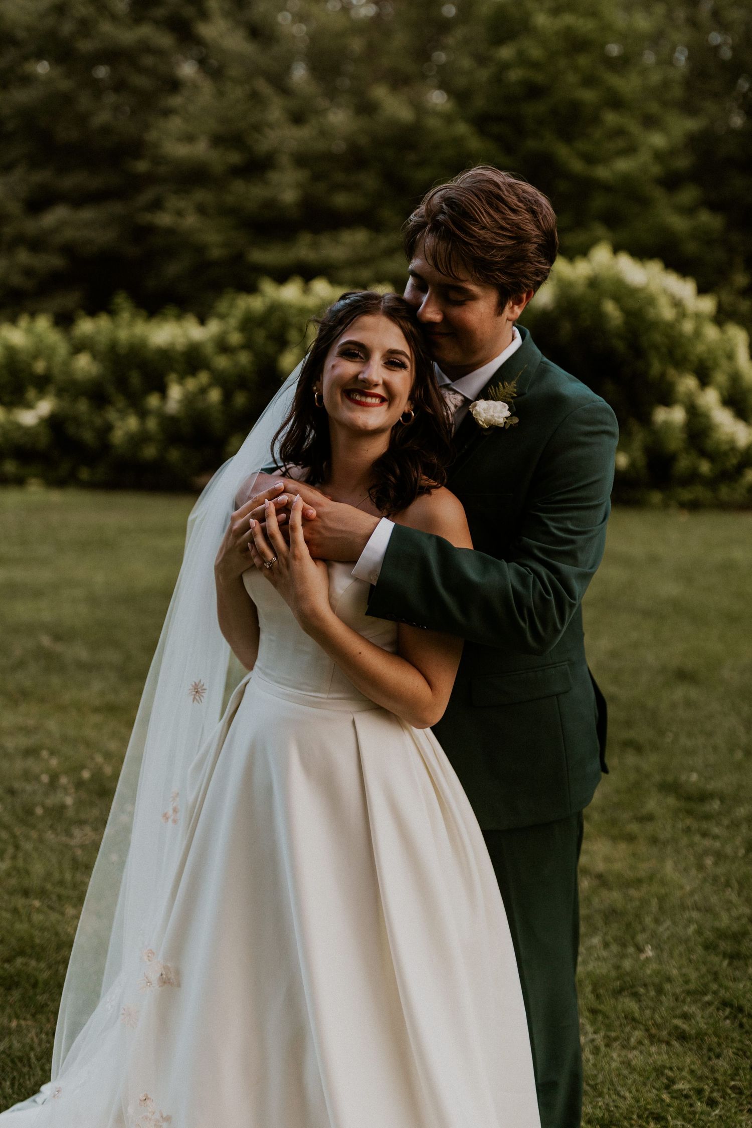 A tender moment between newlyweds in a garden setting with the bride wearing a flowing white gown.