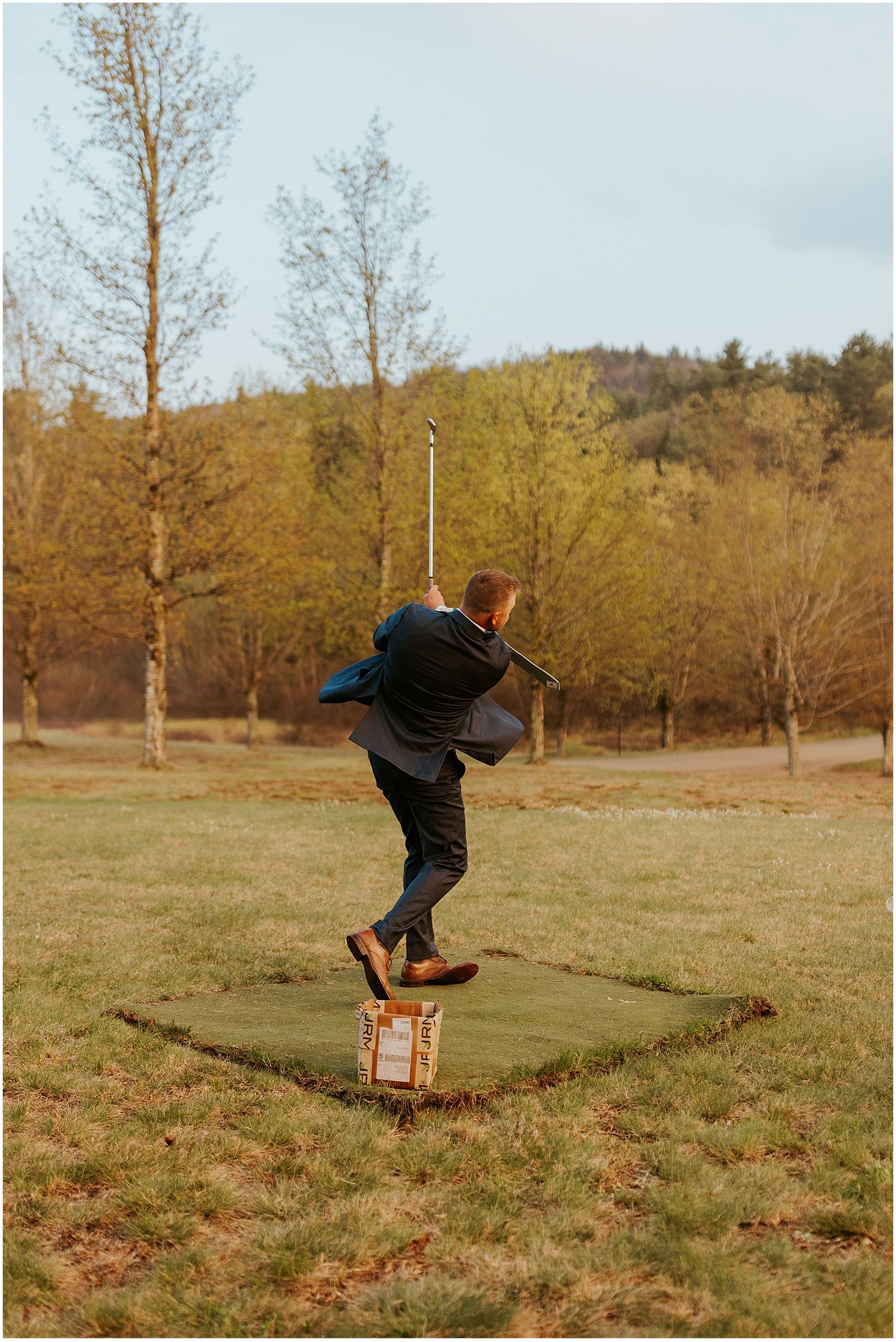 A person performs playful jumps across a grassy field on a sunny day.