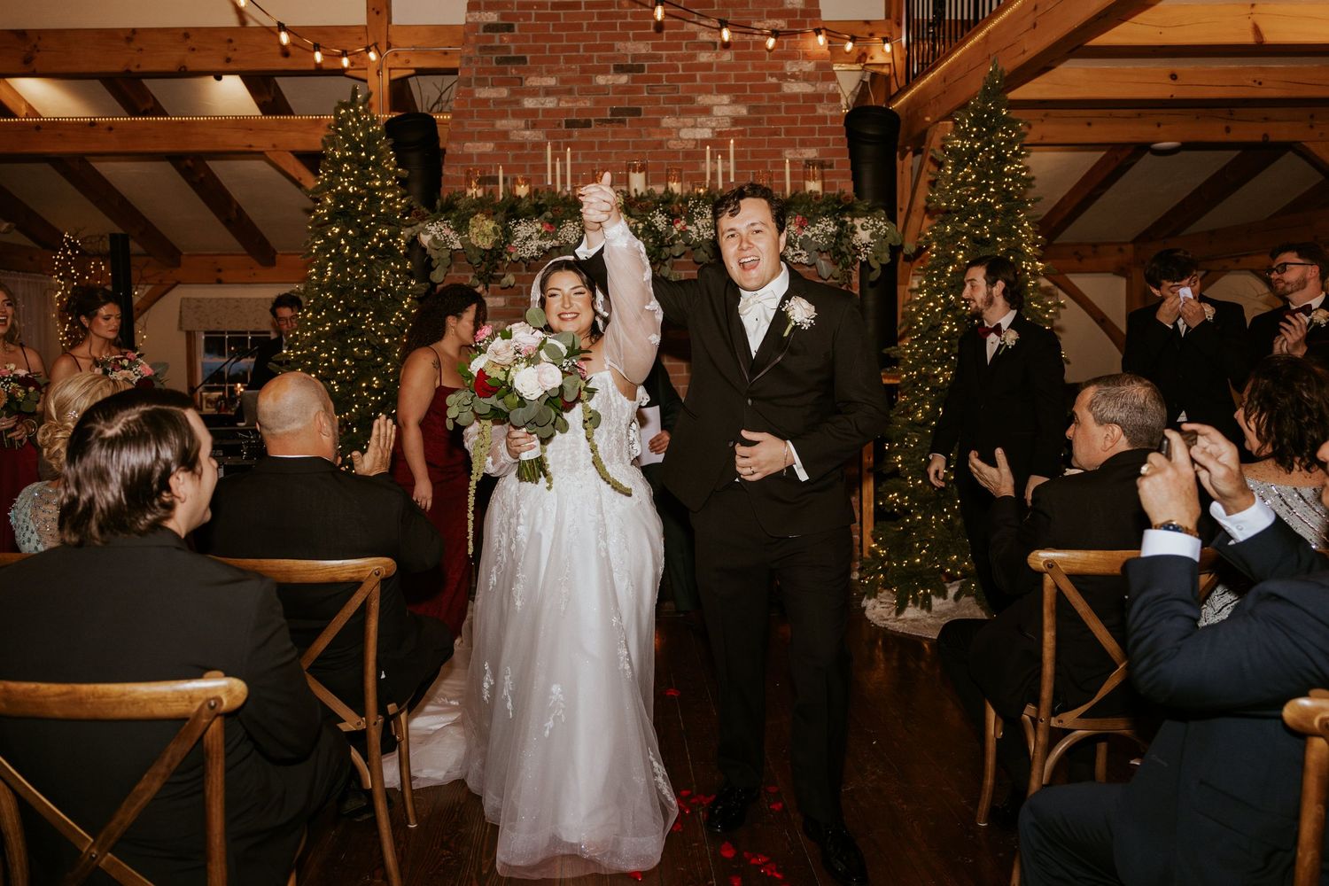 Joyful bride and groom recessional at a festive Christmas wedding ceremony with guests applauding.