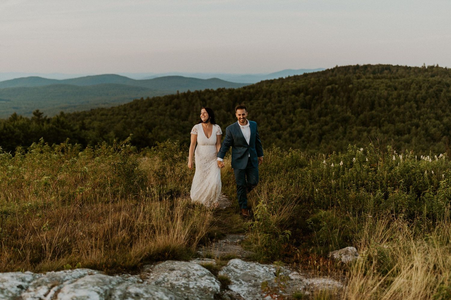 Newlyweds walking together through the fields of the White Mountains.