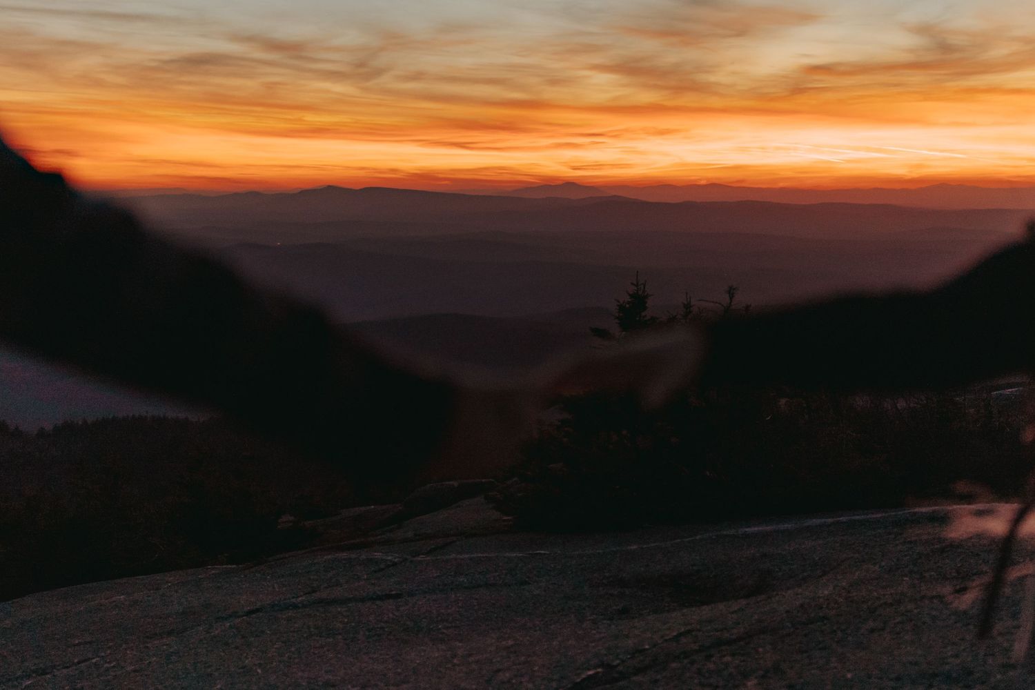 Dramatic orange and purple sunset sky over mountain silhouettes.