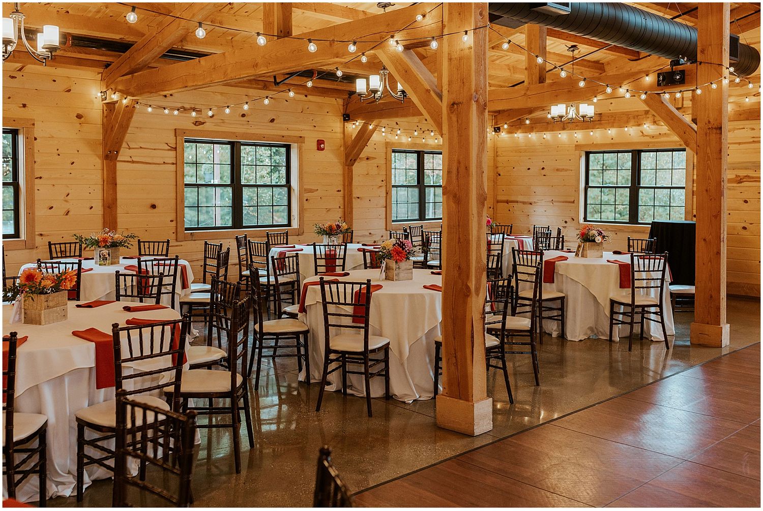 Rustic wooden barn reception venue with elegant table settings and string lights.