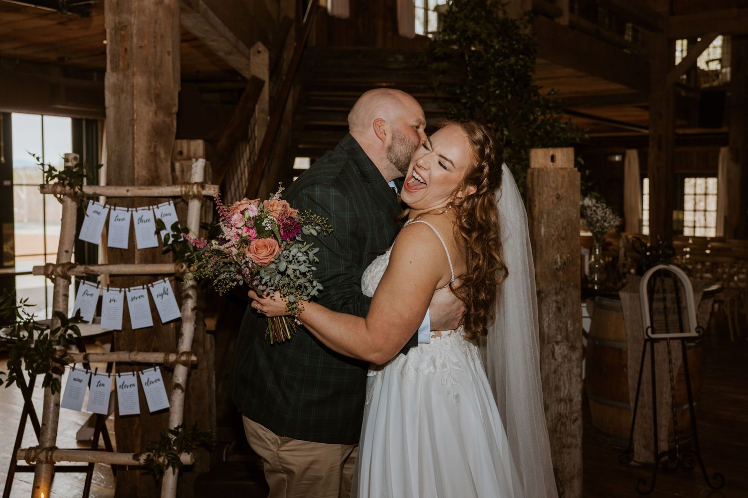 Rustic barn wedding ceremony setup with white draping and wooden beams creating an intimate atmosphere.
