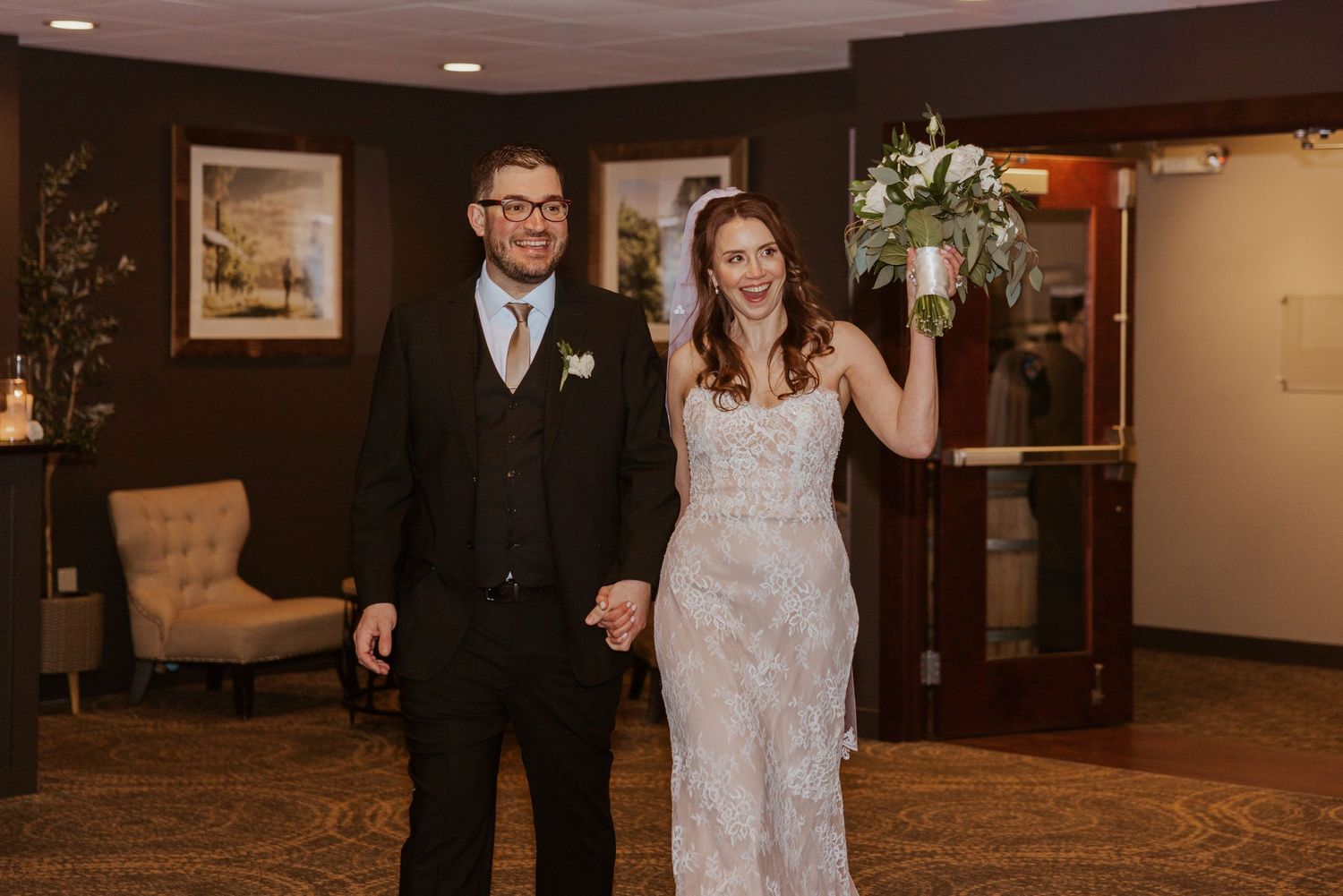 A couple celebrating their wedding day in an elegant indoor venue with dark wood paneled walls.