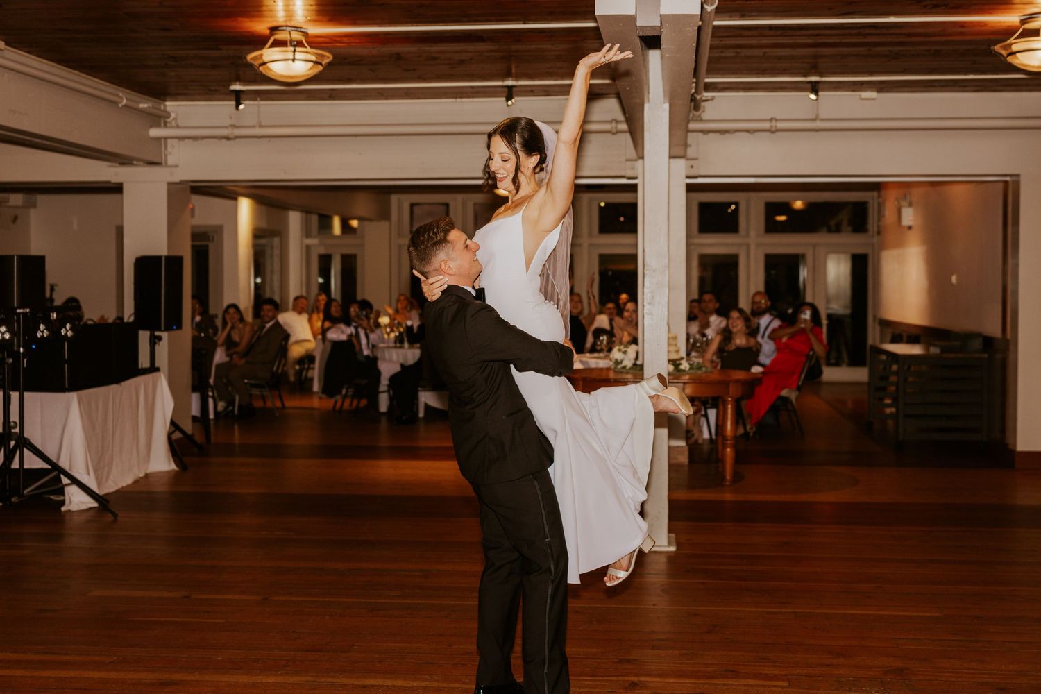 Groom lifting bride during first dance at elegant wedding reception.