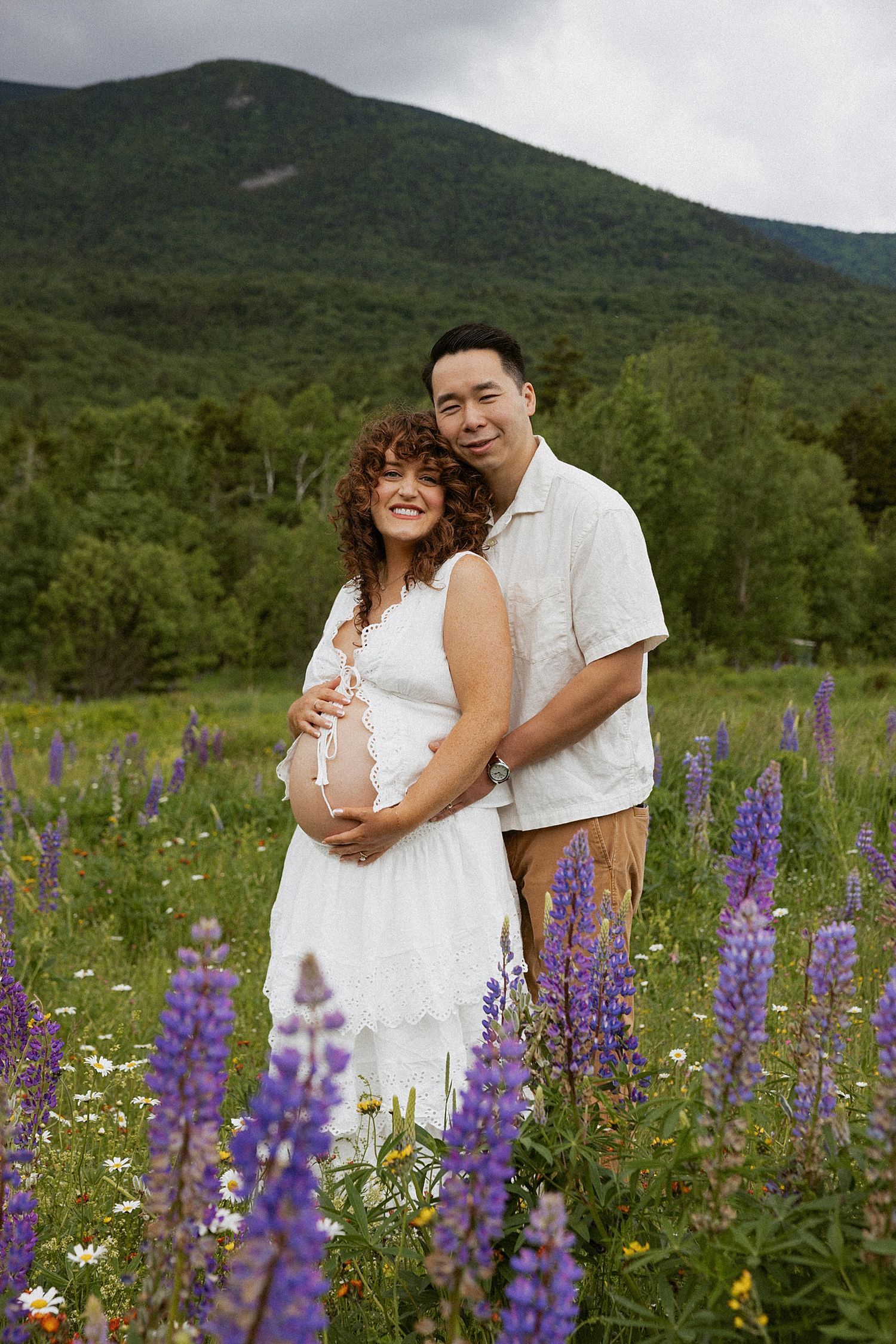 Pregnant couple taking motherhood photos in a lupine field in New Hampshire