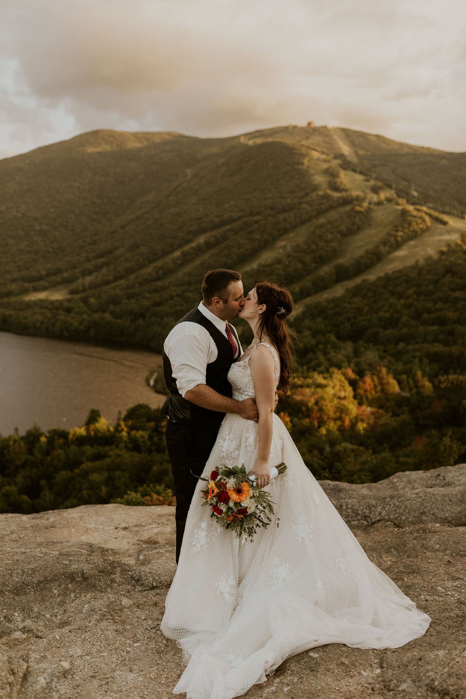 newlyweds kissing on top of the mountain during golden hour.