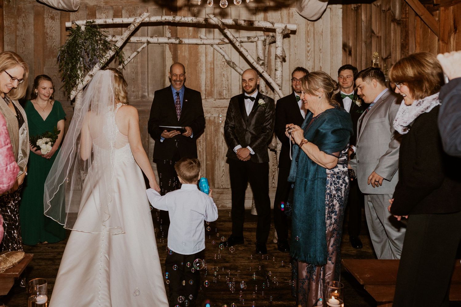 Deirdre and Colby walking down the aisle towards Brodie at their ceremony in the sap house at The Preserve in NH.