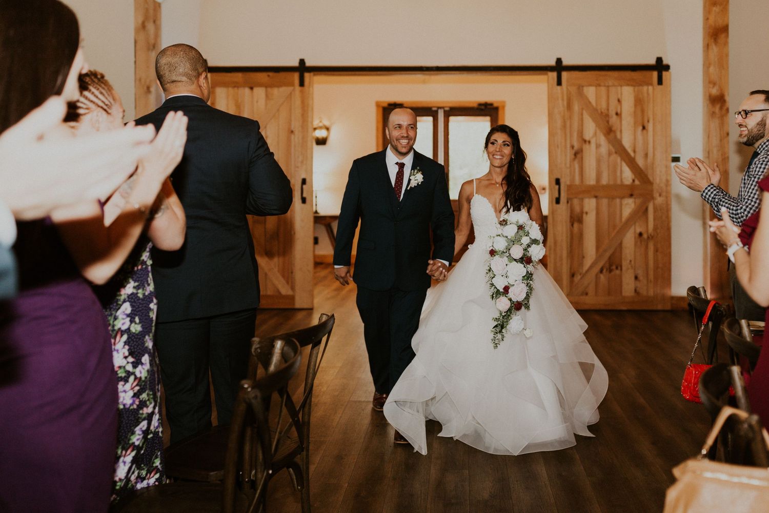 Wedding reception venue with wooden barn interior and dancing guests.