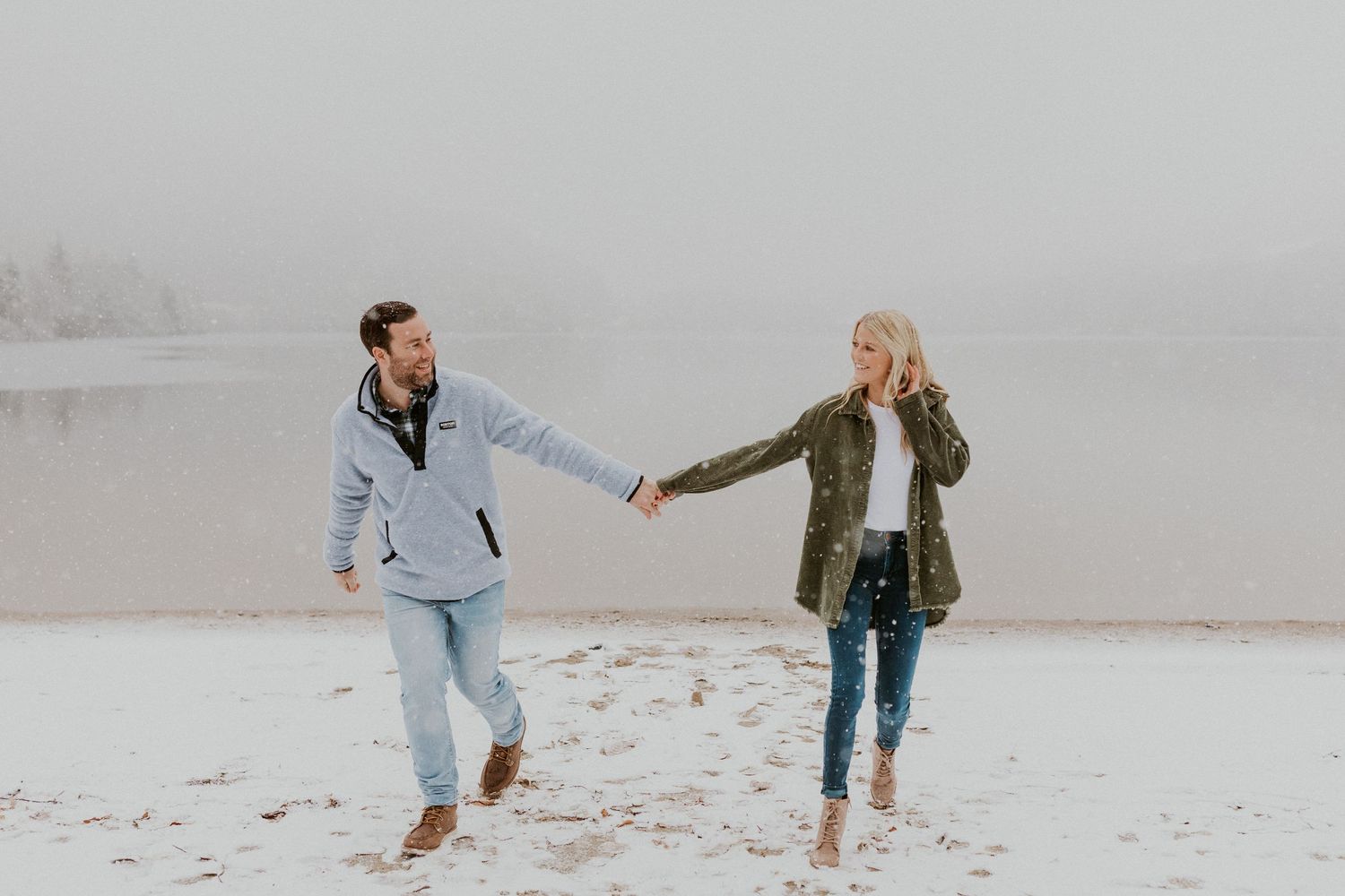 Newly engaged couple playfully walking together during their snowy engagement session in the White Mountains of NH.