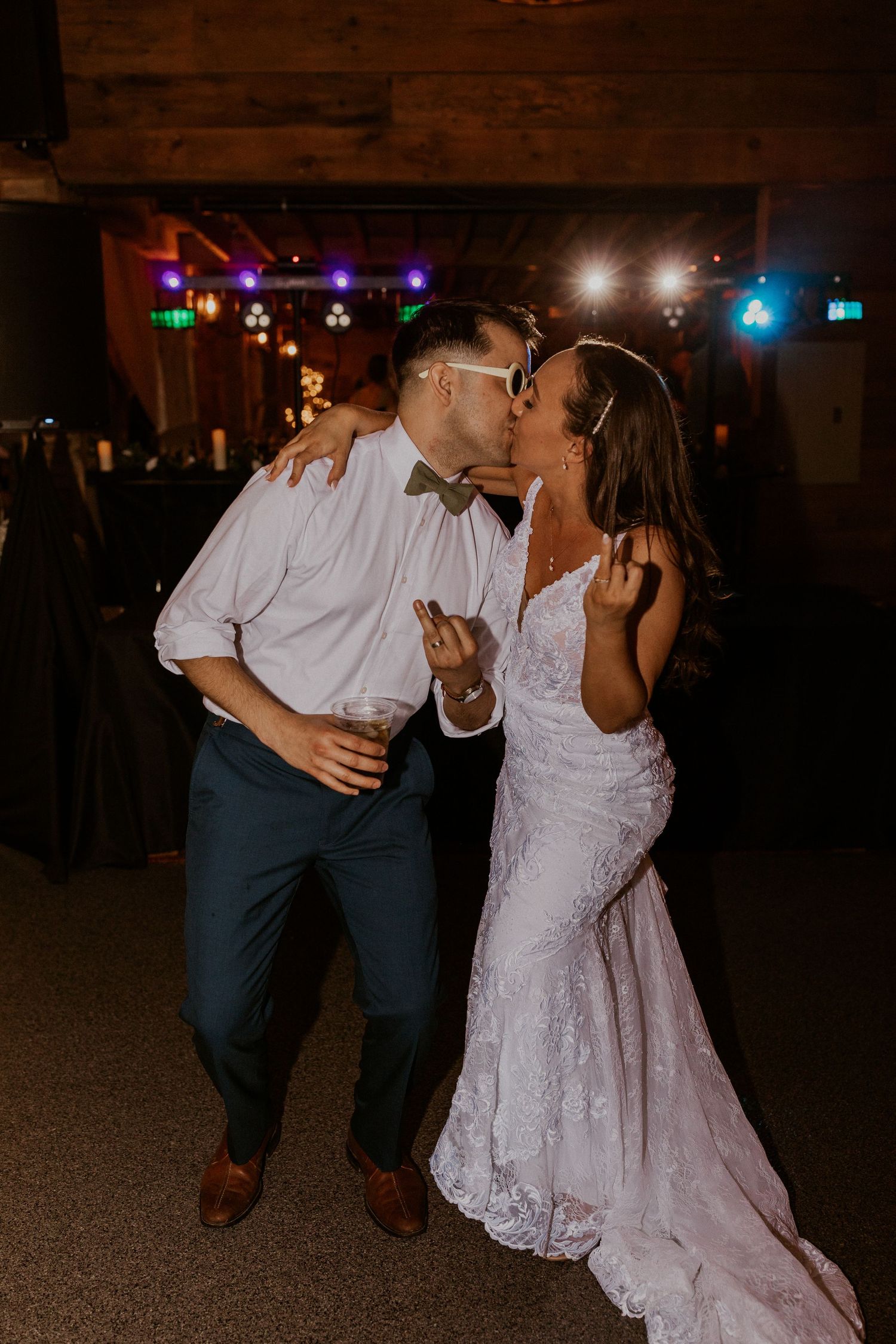 Chrissy and Mike flipping their ring fingers at the camera while kissing on the dance floor.