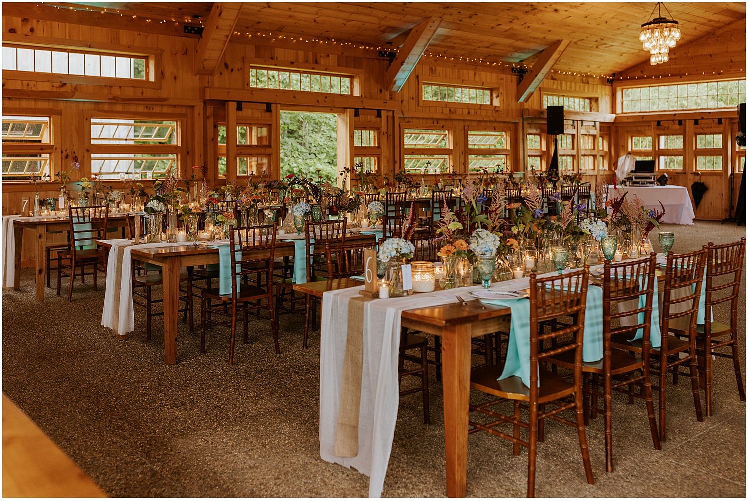 Warm-toned reception hall setup with wooden details and elegant table arrangements for a rustic wedding.