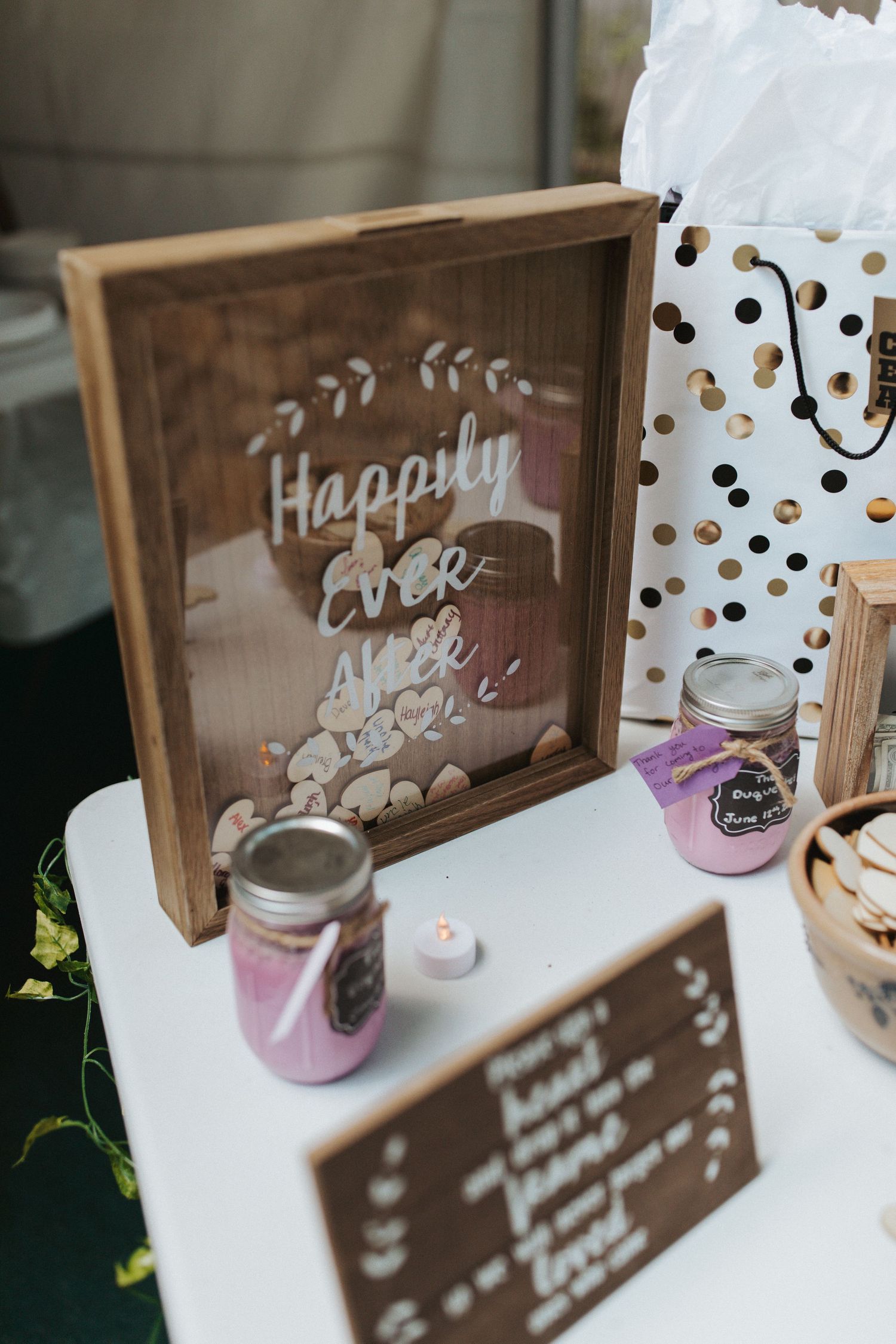 Rustic wooden 'Happily Ever After' sign with wedding decorations and mason jars.