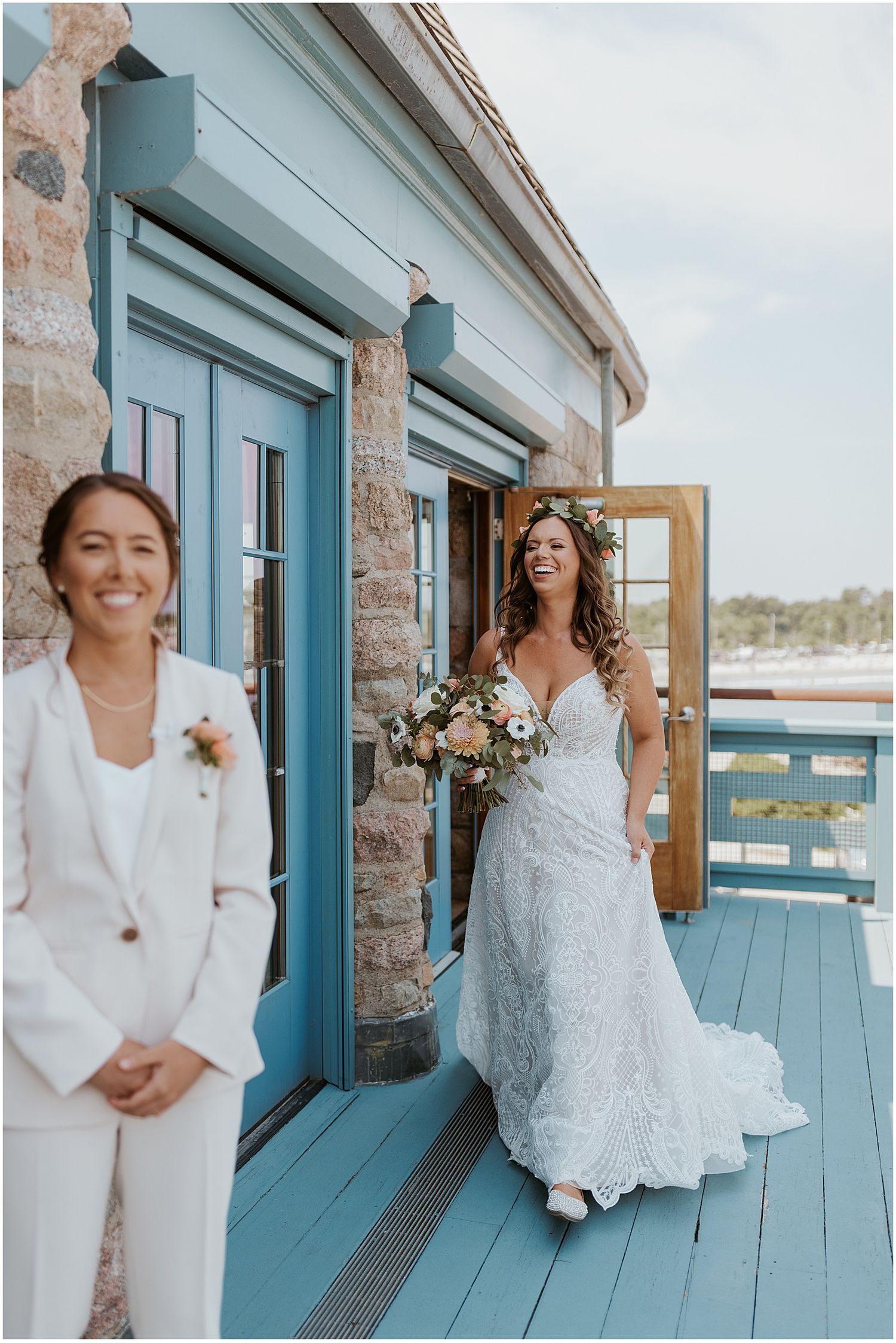 Two people share joyful moments on a blue-trimmed deck overlooking the water.