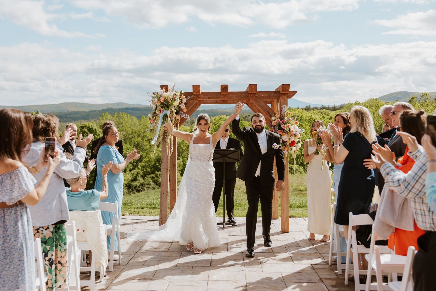 Bride and groom walk back down the aisle after outdoor wedding ceremony at vineyard venue.