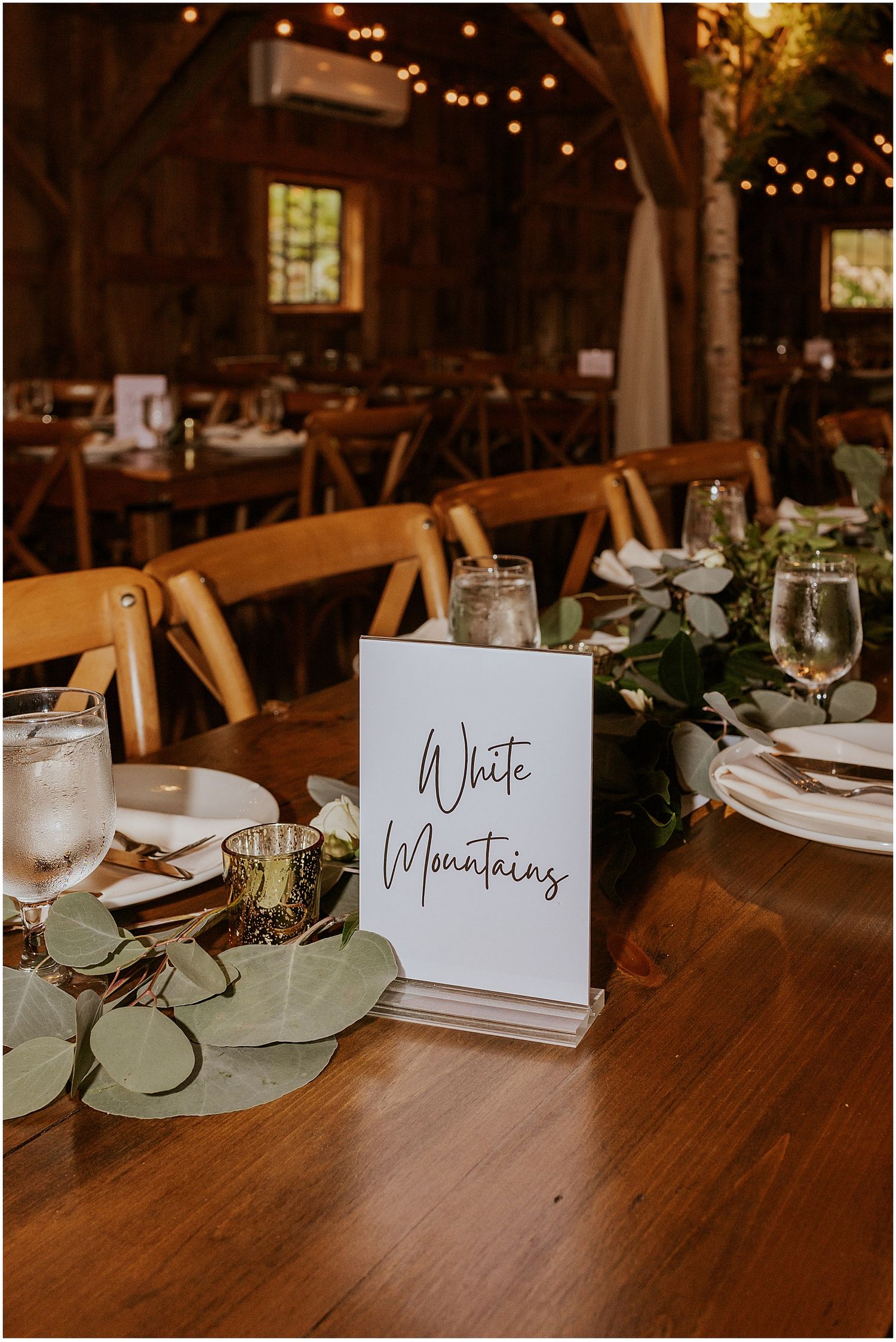 A wedding table number with eucalyptus and votive candles for a NH wedding