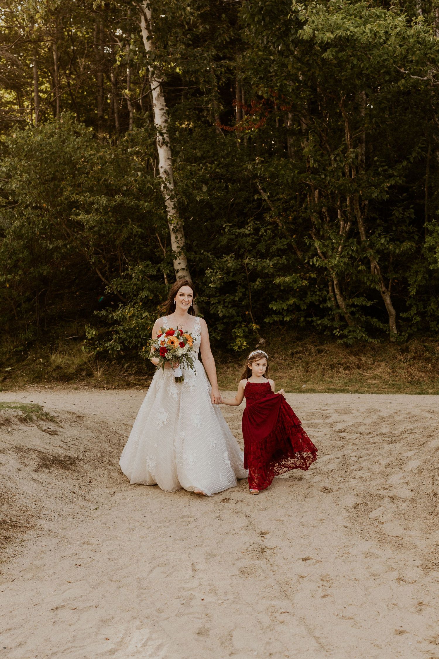 The bride walking down the beach with her daughter to her future husband during their elopement in the white mountains.