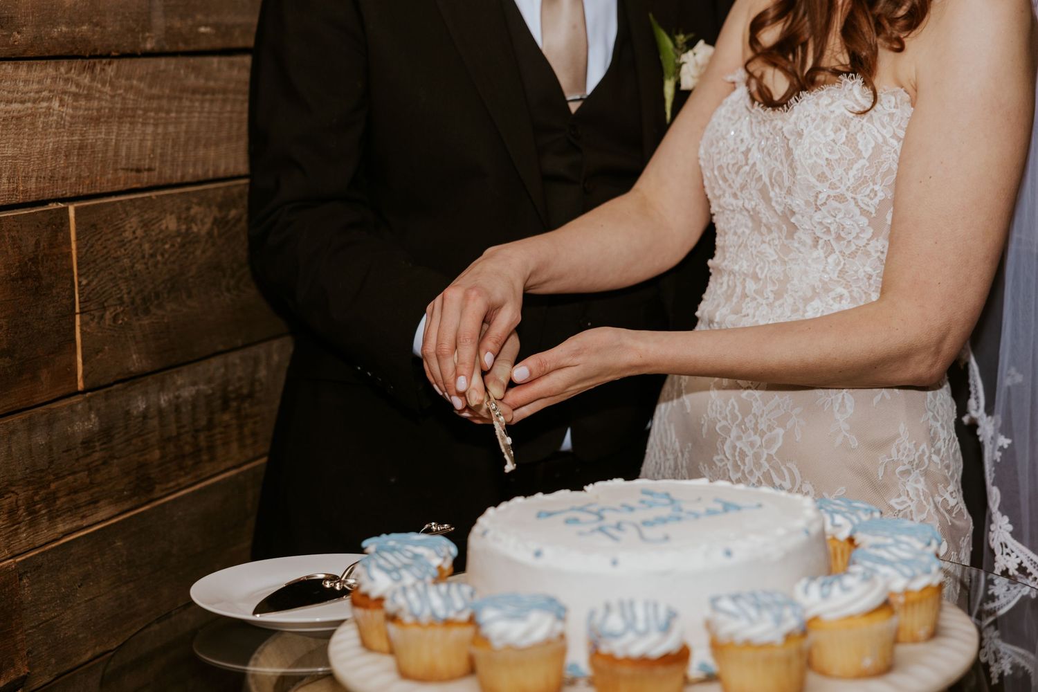 Wedding dessert table with white and blue cupcakes arranged in a rustic setting.