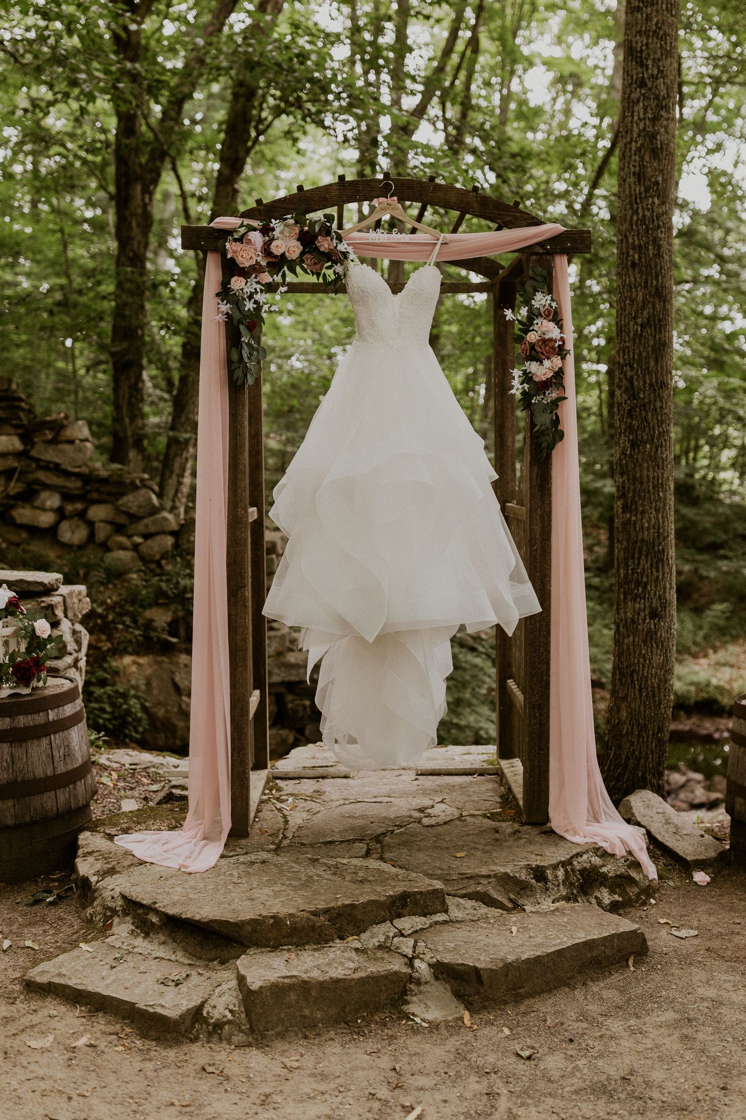 Jessica's dress hanging from the arbor at Wright's Mill Farm. The arbor is decorated with dusty pink, red and white rose
