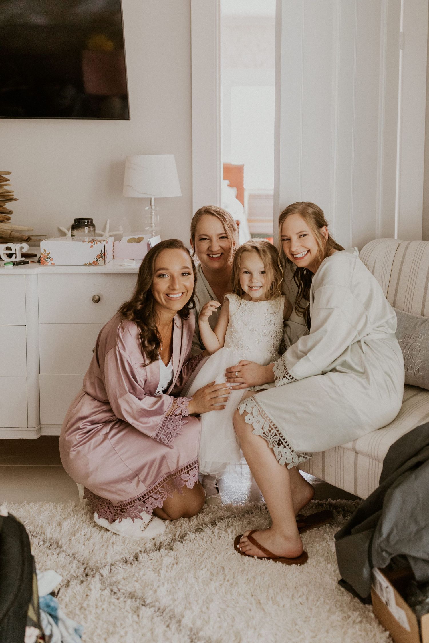 Chrissy and her bridesmaids and flower girl smiling for a photo while getting ready.