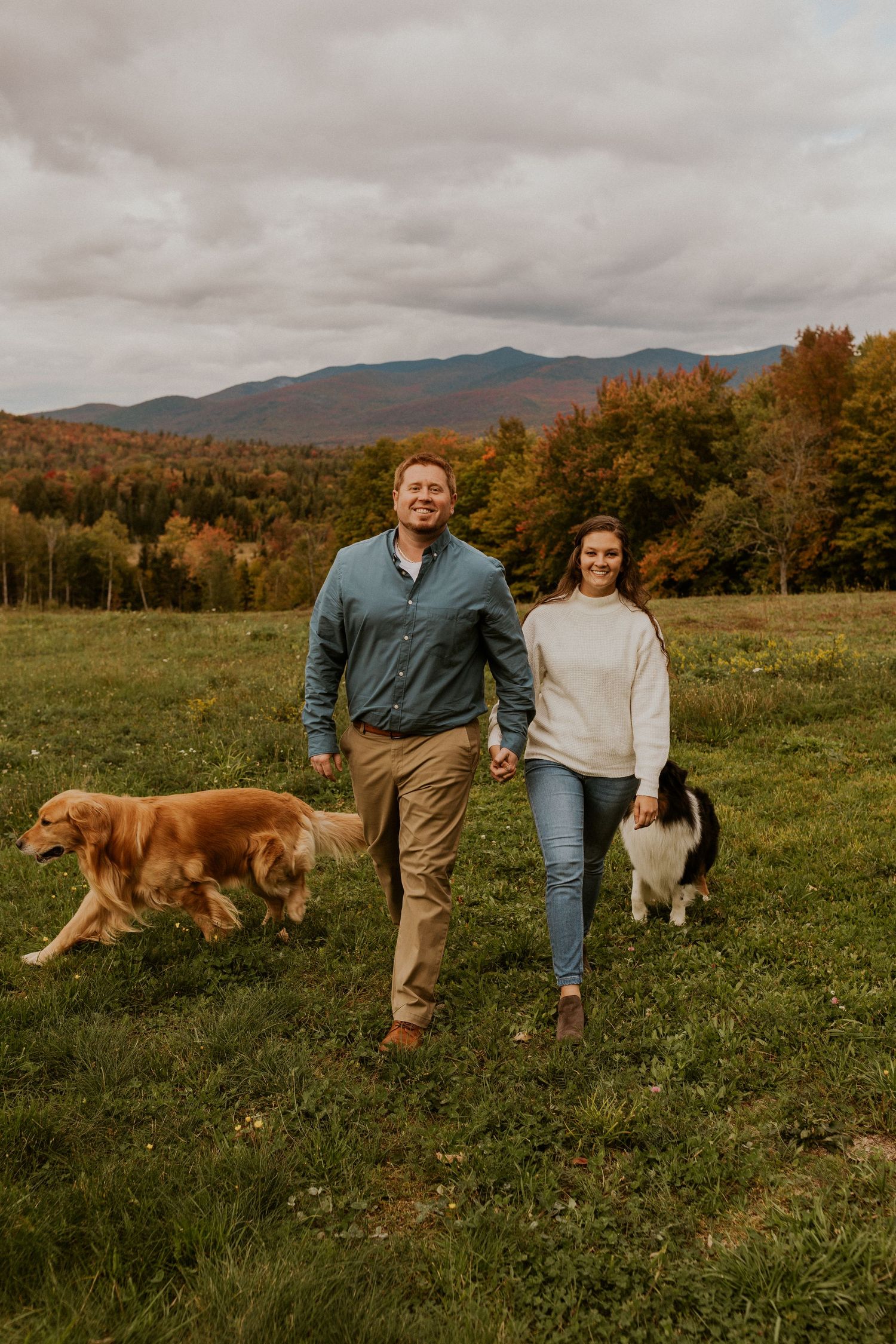 Paige and Michale walking together in a giant field with a mountain view in the white mountains of New Hampshire