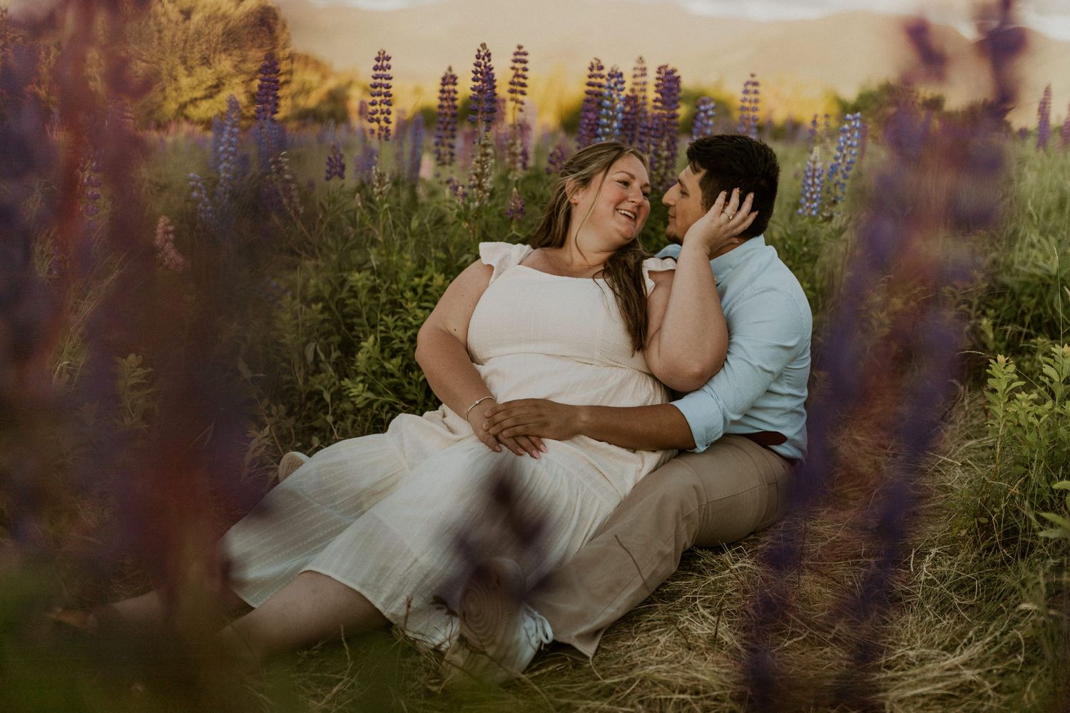 Terise and Jose cuddling up together in a field of purple lupines in Sugar Hill New Hampshire.