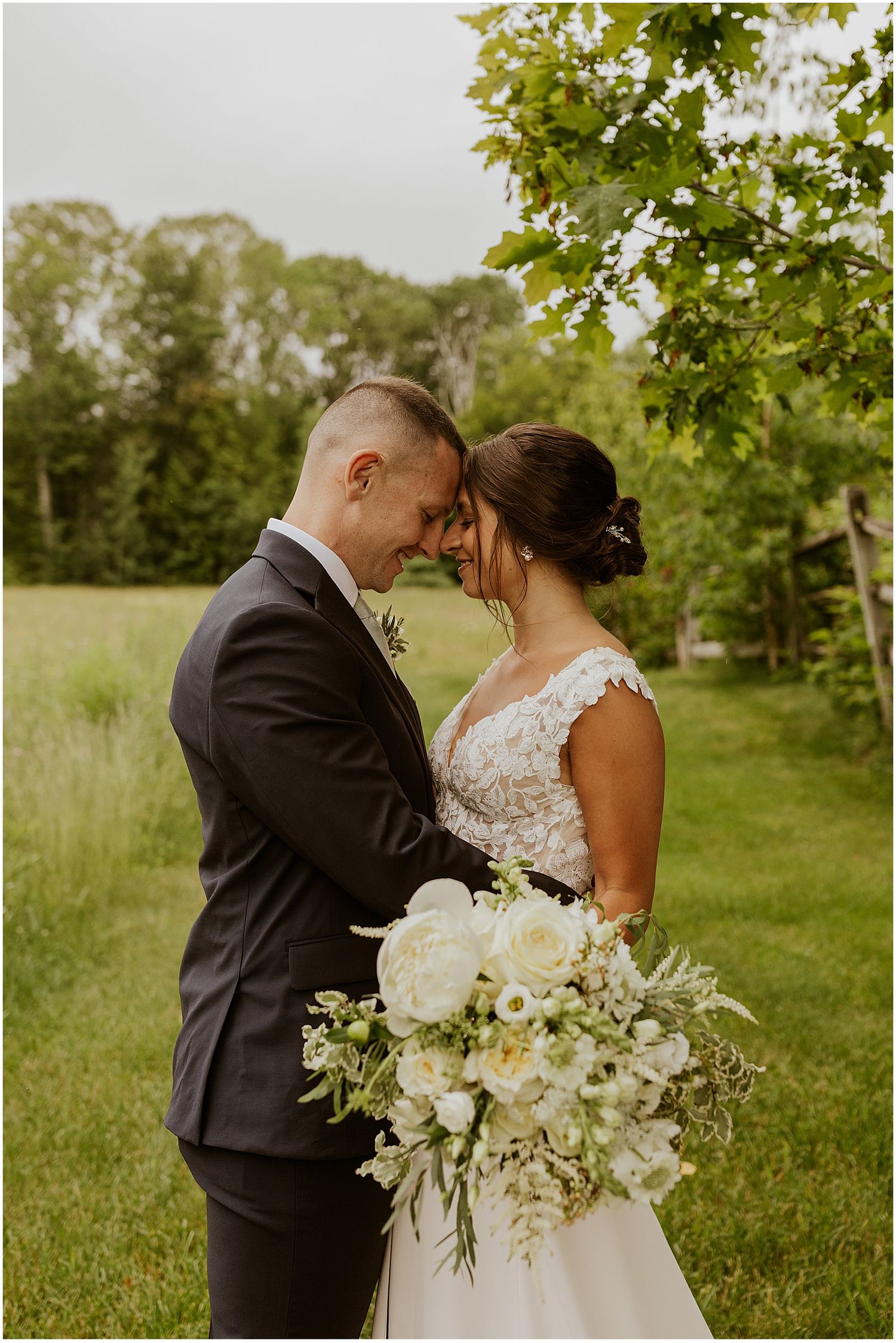 An intimate moment captured in a lush green garden setting with white floral bouquet.