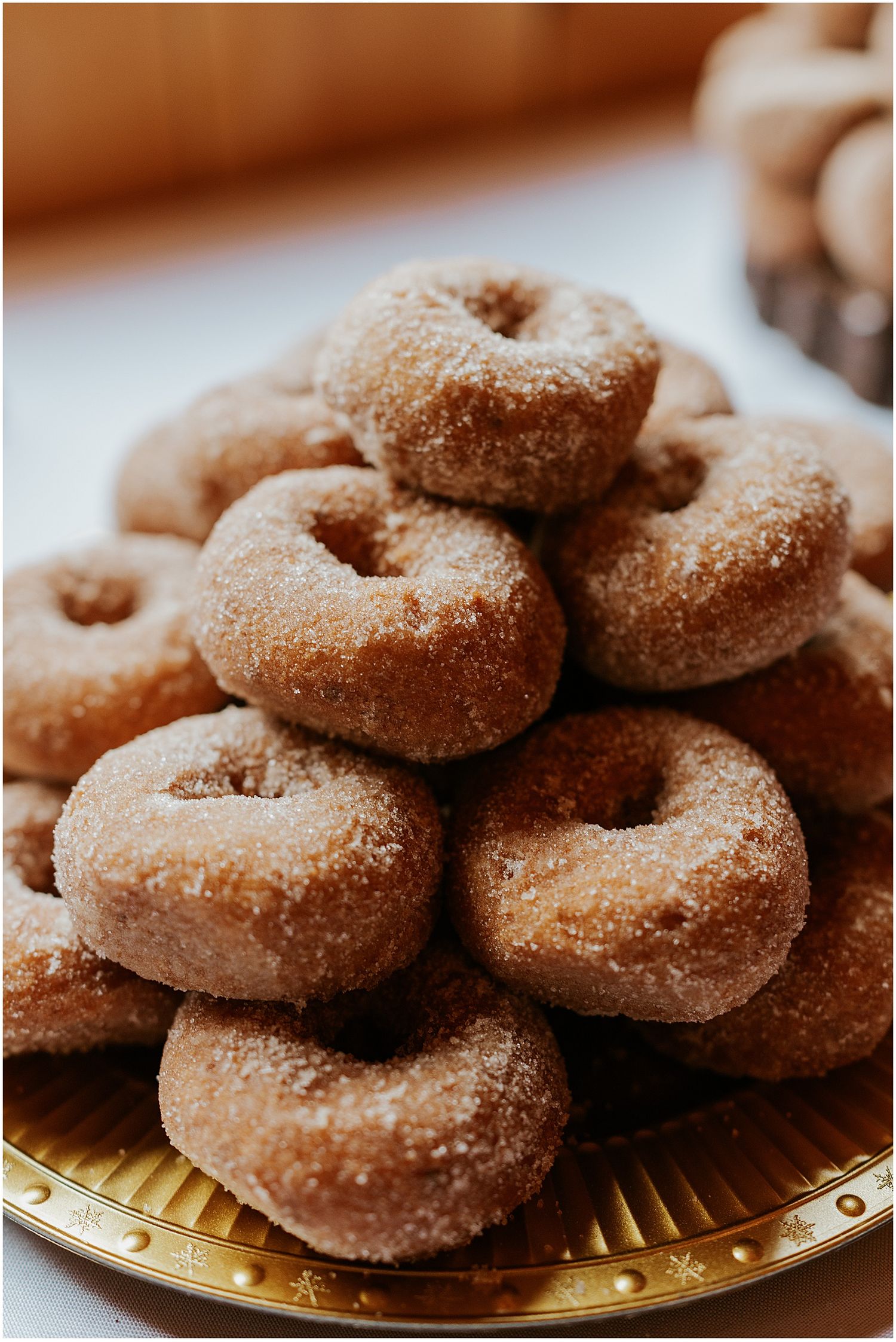 Fresh homemade cinnamon sugar donuts arranged on a gold serving plate.