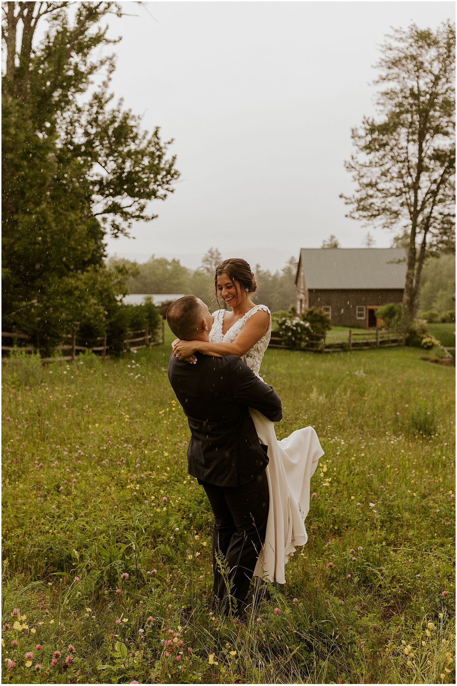 A romantic dance in a wildflower meadow with rustic buildings in the background.